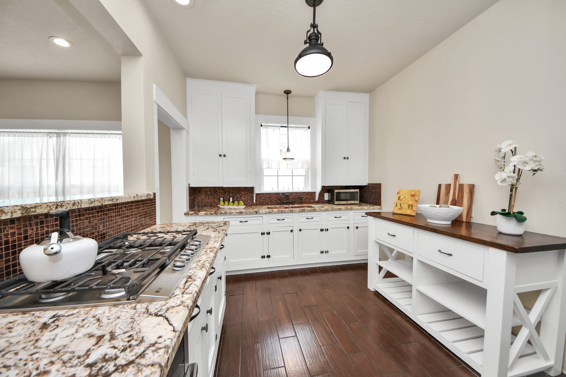 Designed for both everyday living and entertaining, the kitchen features granite countertops, a gas cooktop, abundant cabinetry, and a charming butcher block island.