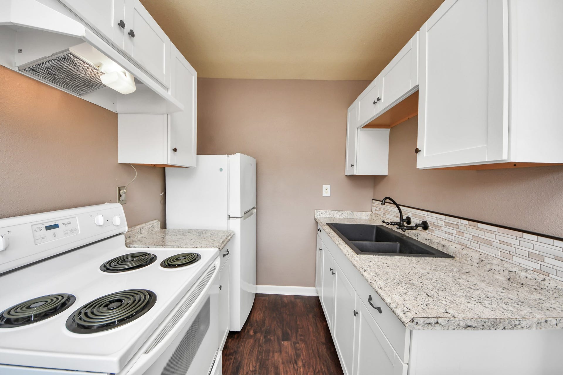Fully equipped guest home kitchen with ample cabinet storage, granite countertops, and hardwood floors.