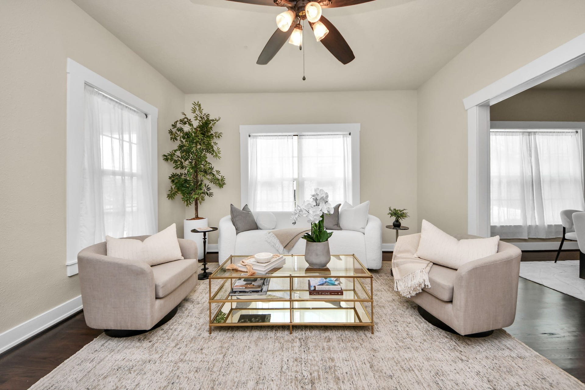 Step into a bright and inviting living room boasting large windows allowing natural light to fill the space, enhancing the warm and welcoming atmosphere.