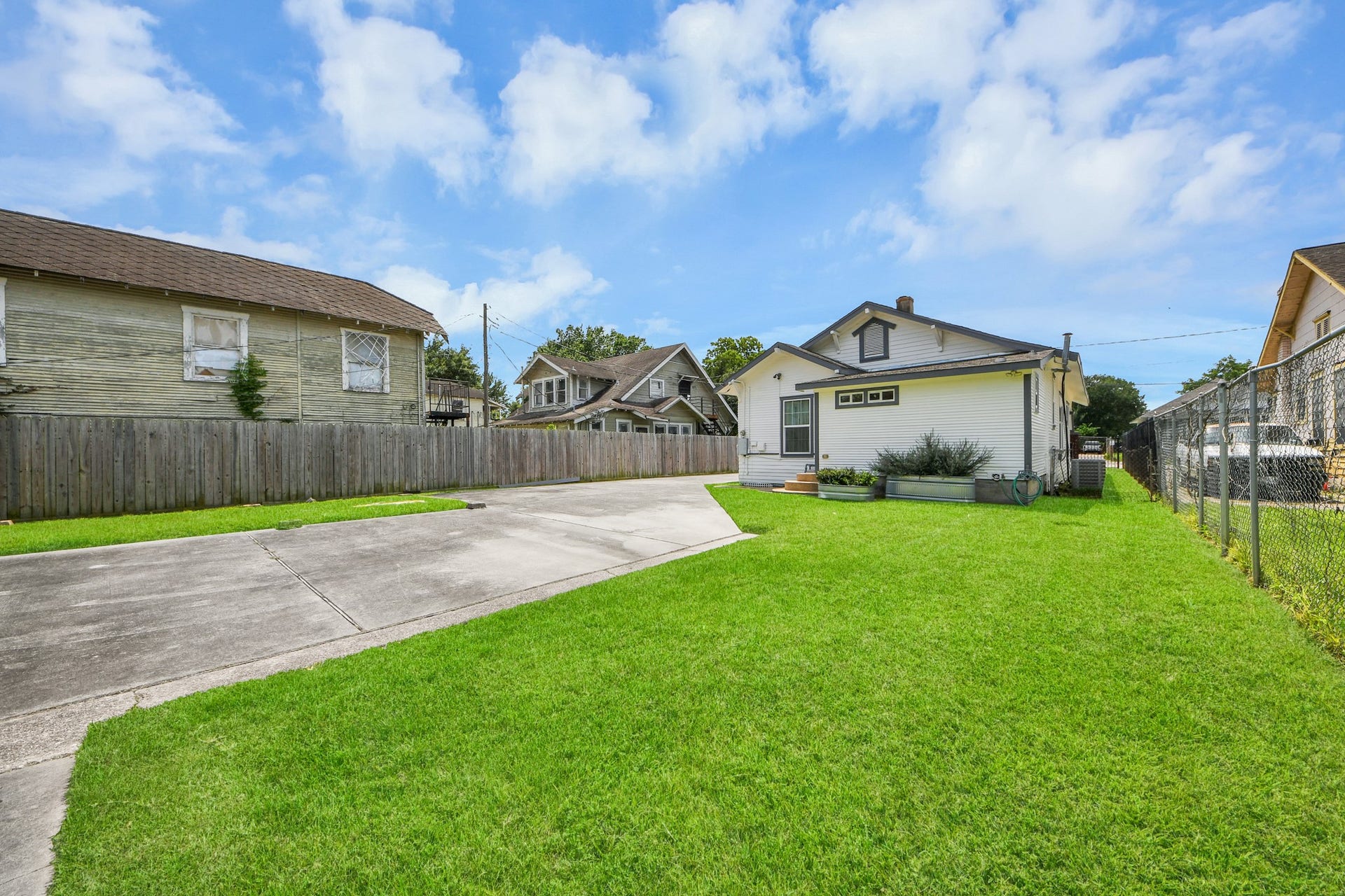 Expansive, lush yard with plenty of green space, extended concrete driveway, and privacy fencing.