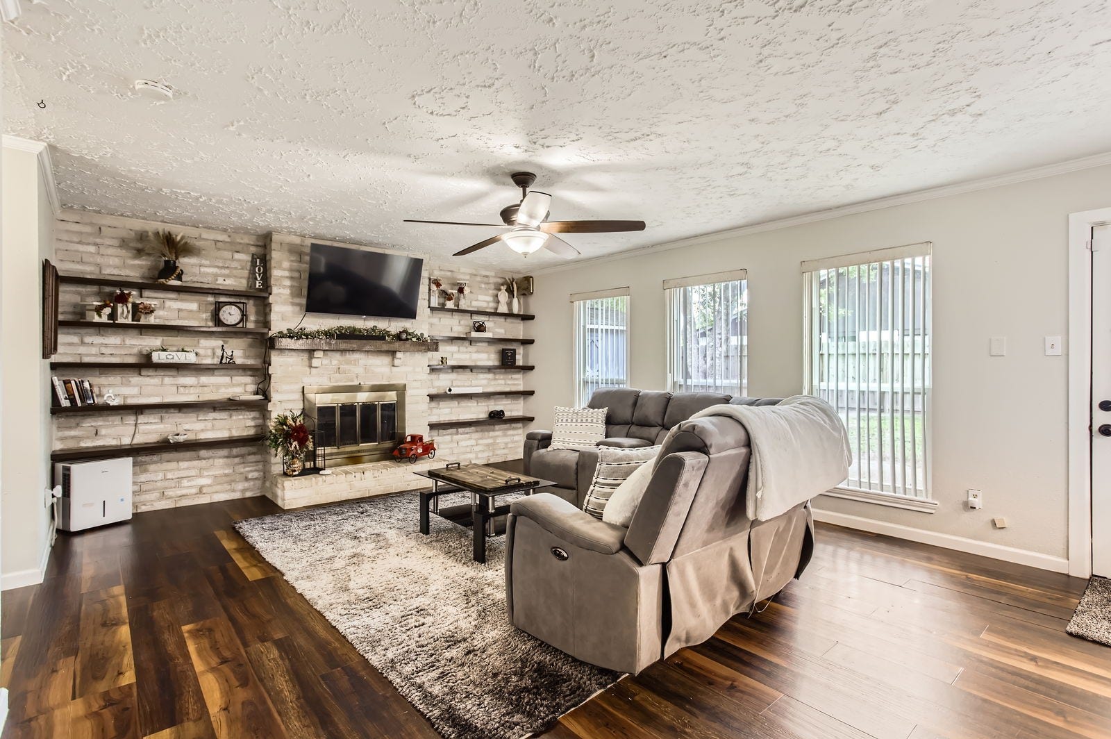 The family room also include a brick fireplace and accent wall with built-in shelving.