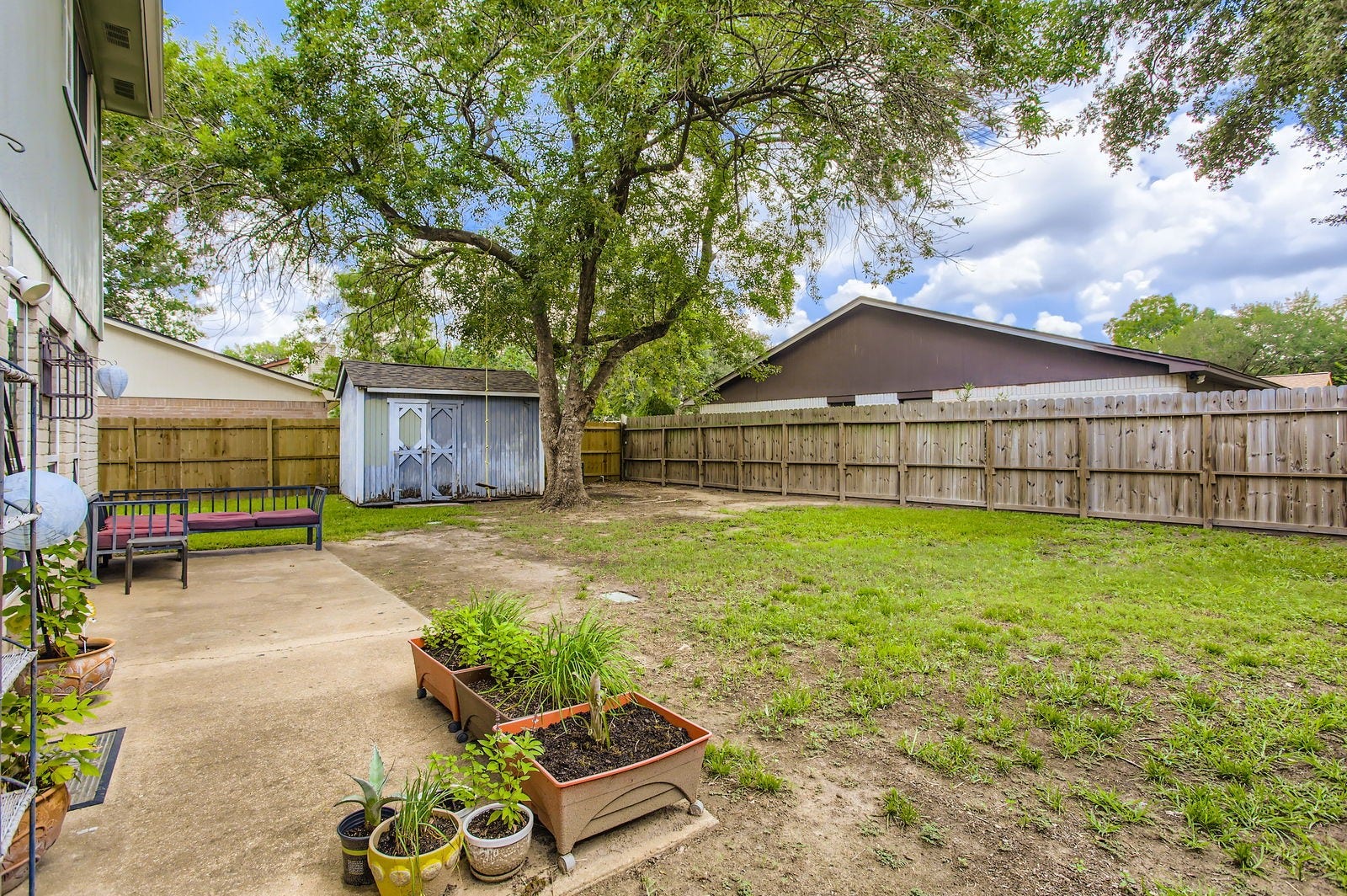 Huge backyard features an oversized patio and storage shed.