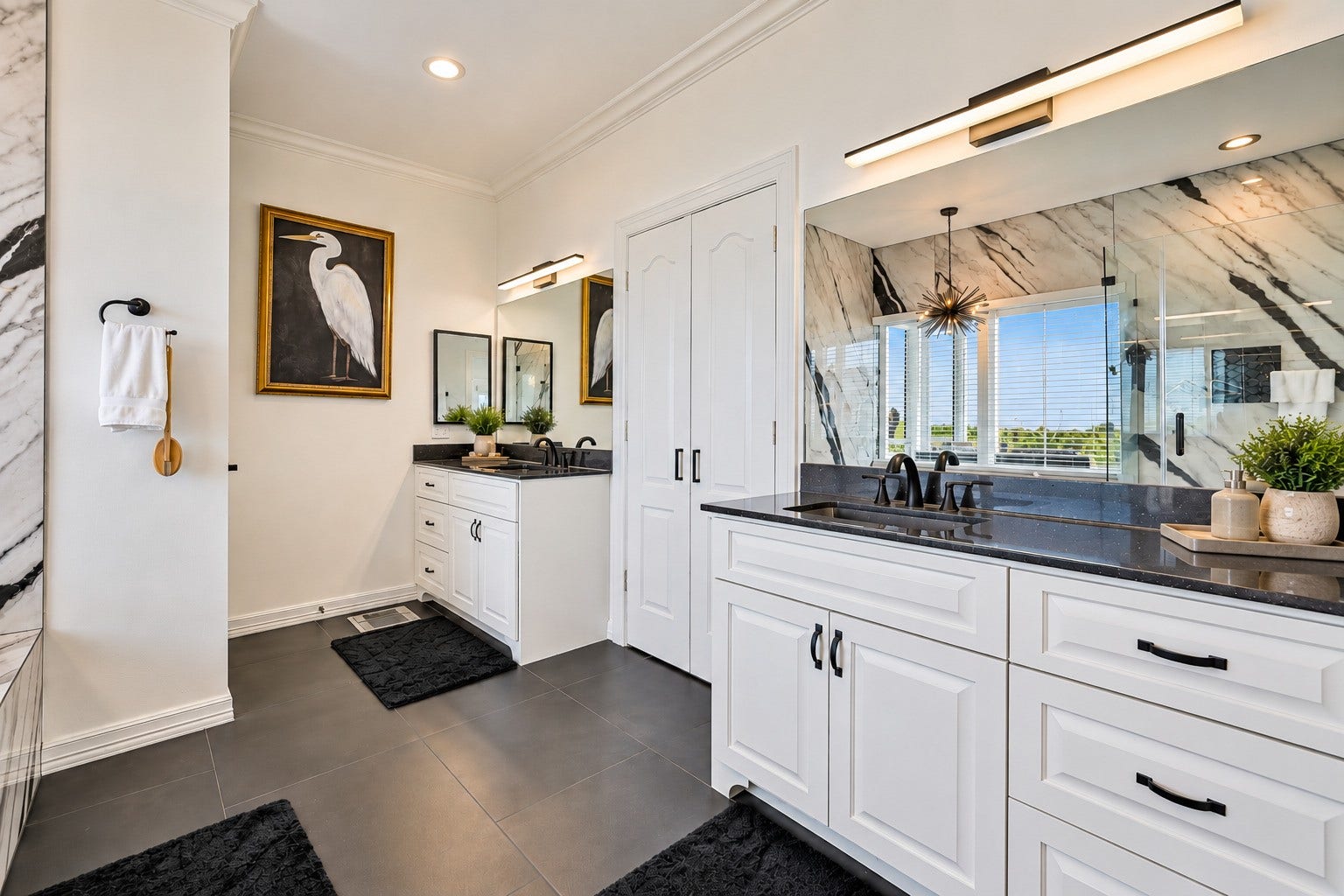 12 Fleming, Hitchcock, TX 77563 Floor-to-ceiling custom tile work. Black-framed modern glass shower doors. Shower niche built into the wall. Poured granite double sinks. A soaking jacuzzi tub positioned to enjoy the natural light. The primary bath at 12 Fleming was not updated it was completely reimagined from scratch as part of the full 2025 luxury rebuild. The difference is visible in every single detail.