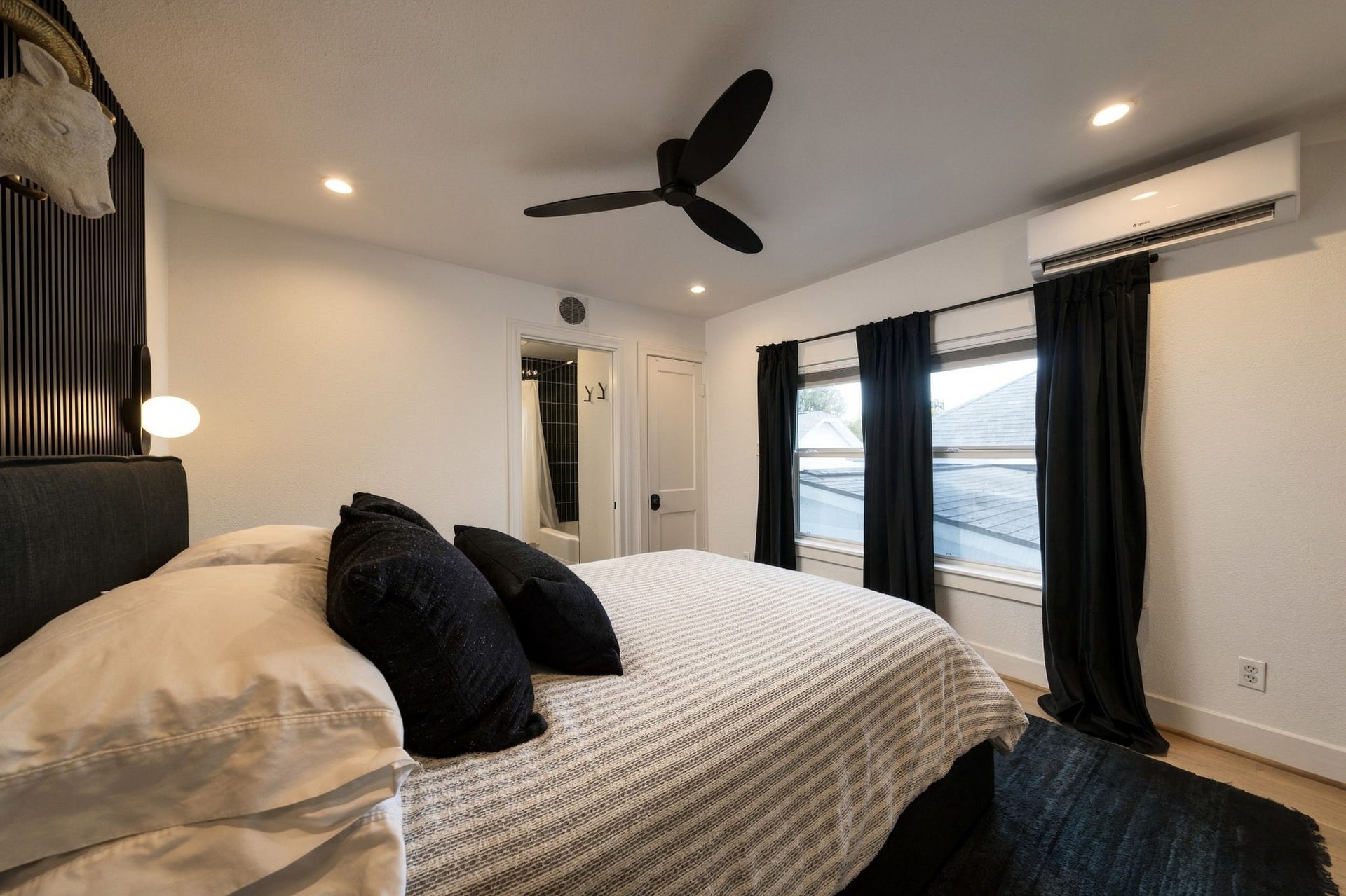 Bedroom accommodates a king sized bed. Accent wall with fluted wood and double windows.