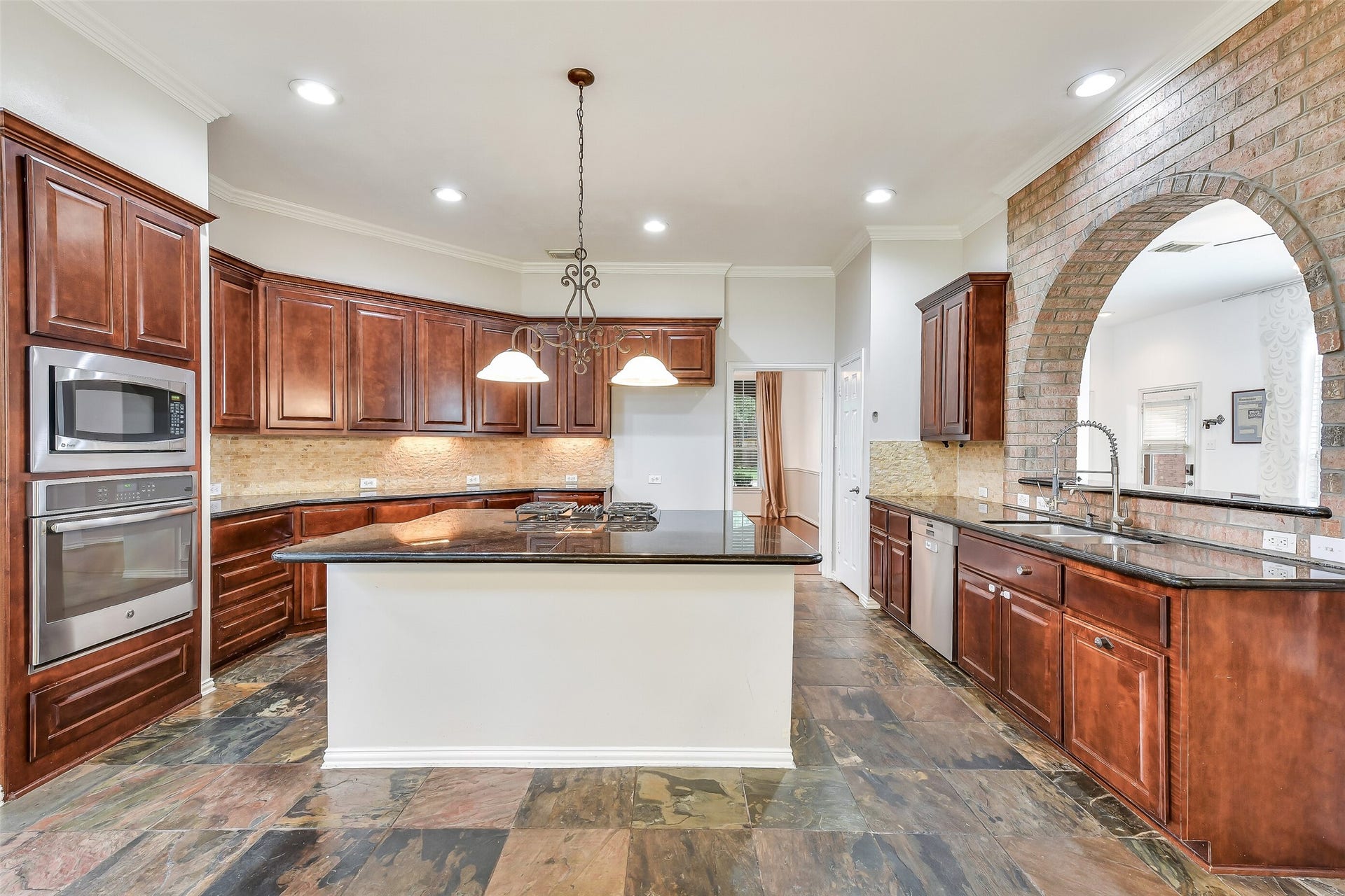 8407 Alyssa Gardens Lane, Humble, TX 77396 An entertainer and chef's dream, this kitchen boasts a massive island with seating for four, GE gas cooktop, generous cabinetry, under-cabinet lighting, built-in microwave and range, all set against a stylish brick accent wall.