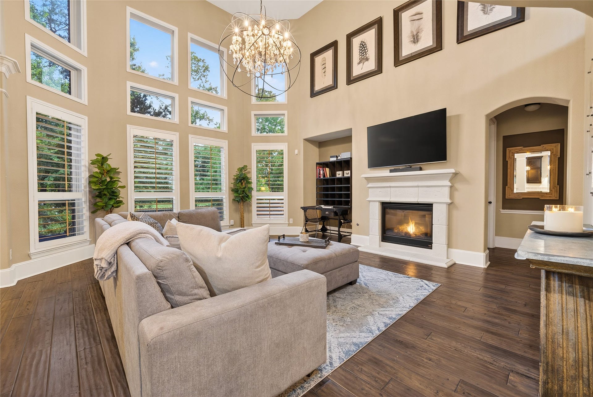 The open layout is complemented by a stunning modern chandelier, elegant wood flooring, and a warm and stylish atmosphere.