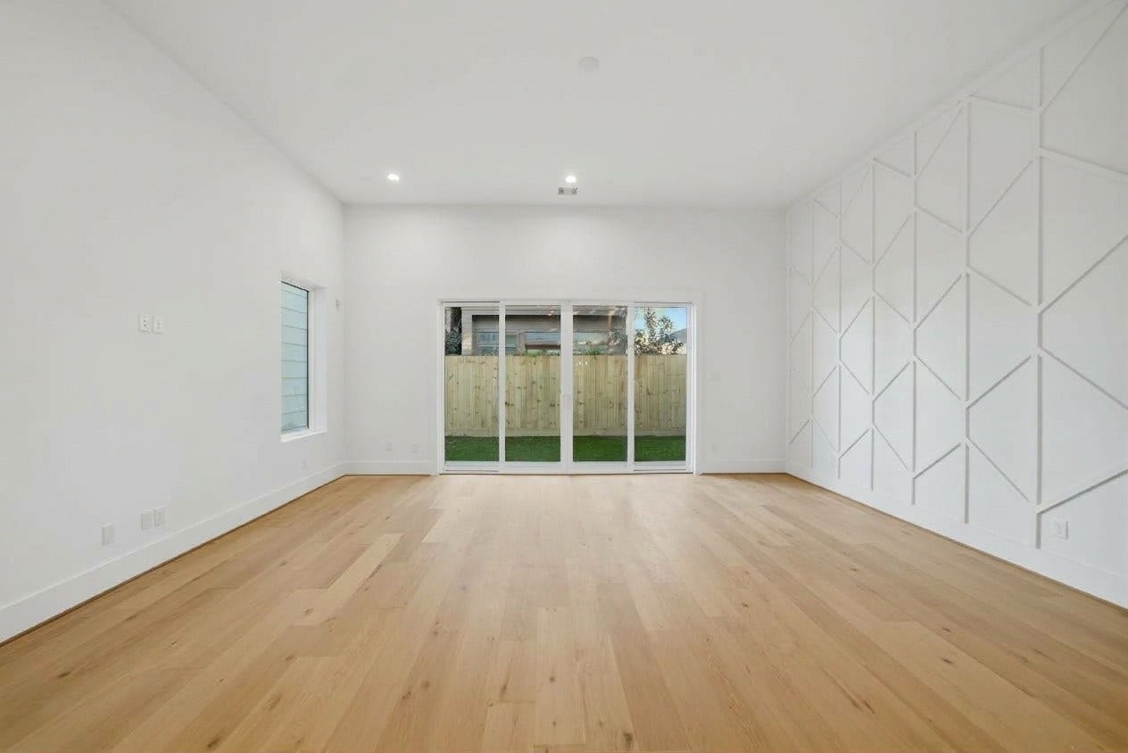 1322 Lawrence Street, Houston, TX 77008 Featuring soaring ceilings, light modern hardwood floors, and a striking geometric feature wall, this bright open-concept living space is perfect for modern living. Large wall-to-wall sliding glass doors flood the room with natural light and open directly to a private, fully fenced backyard area