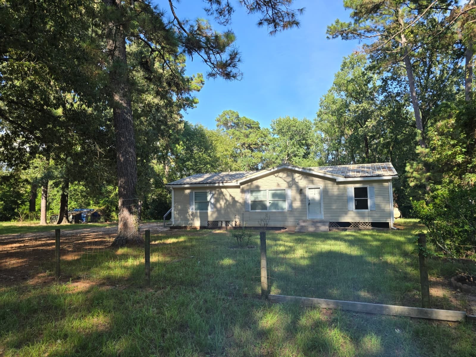 Charming single-story home nestled among tall trees, offering a serene and private wooded setting.