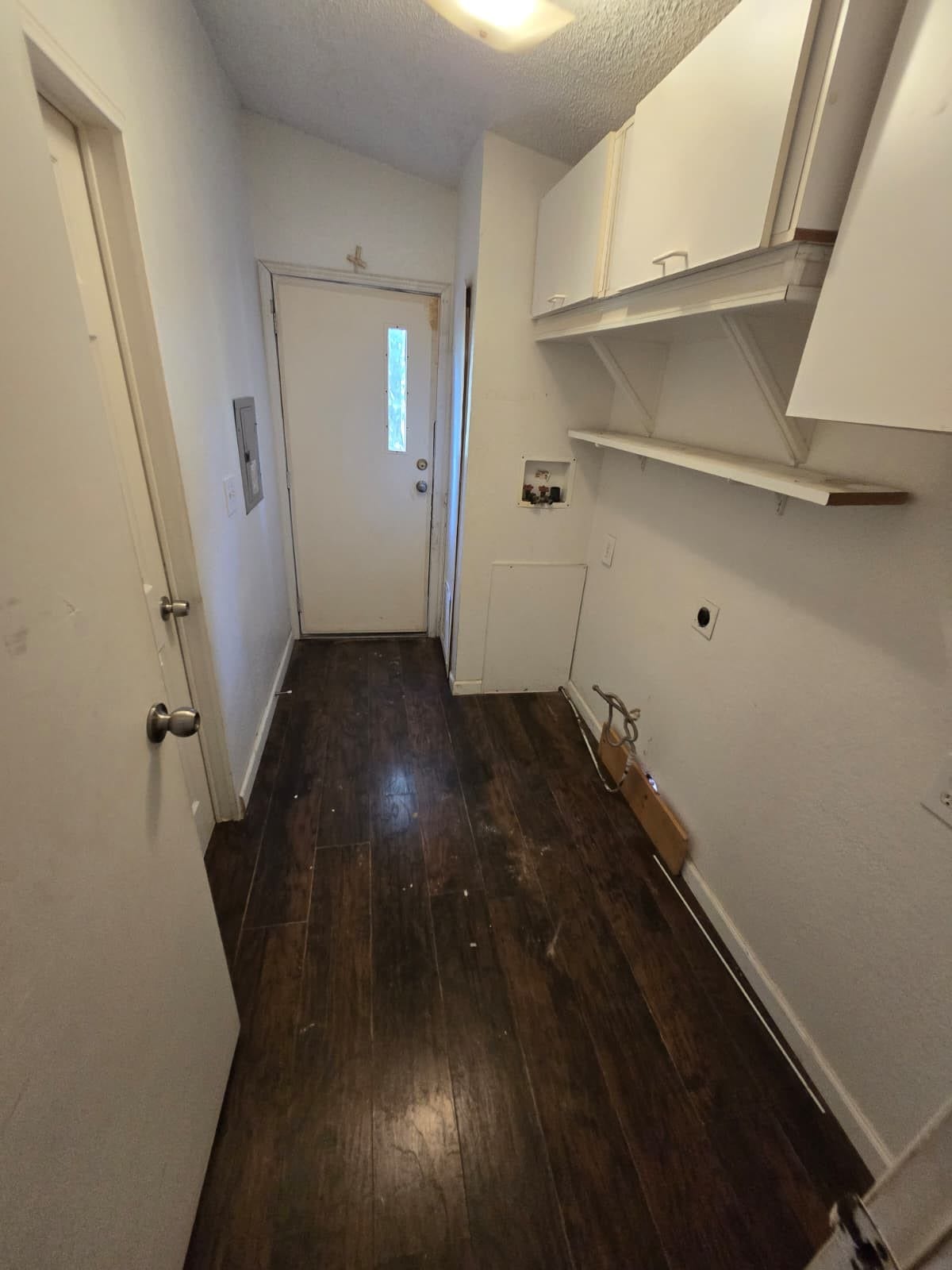 Cozy laundry room with dark wood flooring, ample storage cabinets, and convenient shelving, offering functional space for household tasks.