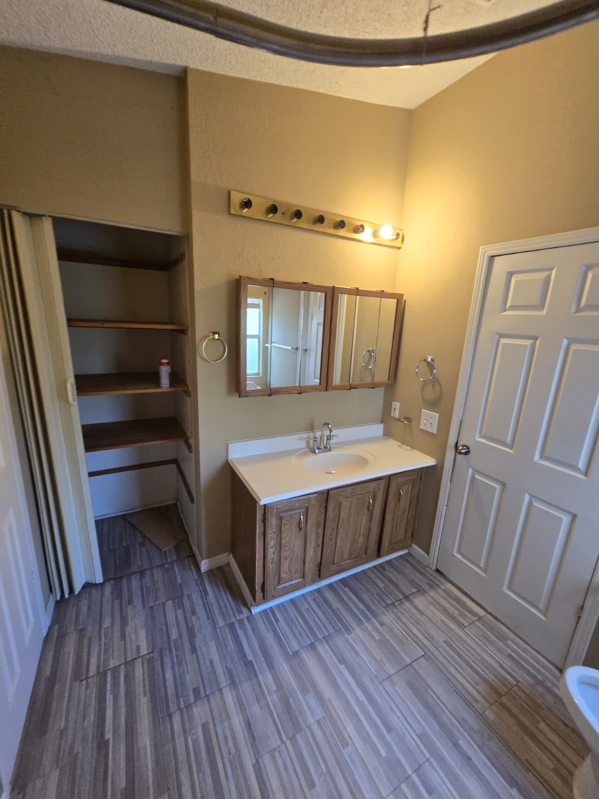 Spacious bathroom featuring a sleek single vanity with ample storage, stylish wood cabinetry, and modern tile flooring, alongside convenient open shelving.