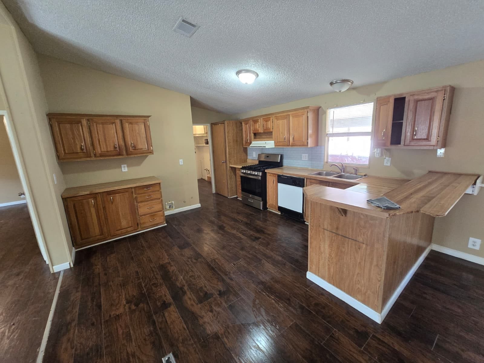 Spacious kitchen with rich wood cabinetry, sleek countertops, and modern appliances, complemented by warm, dark flooring for a cozy and inviting atmosphere.