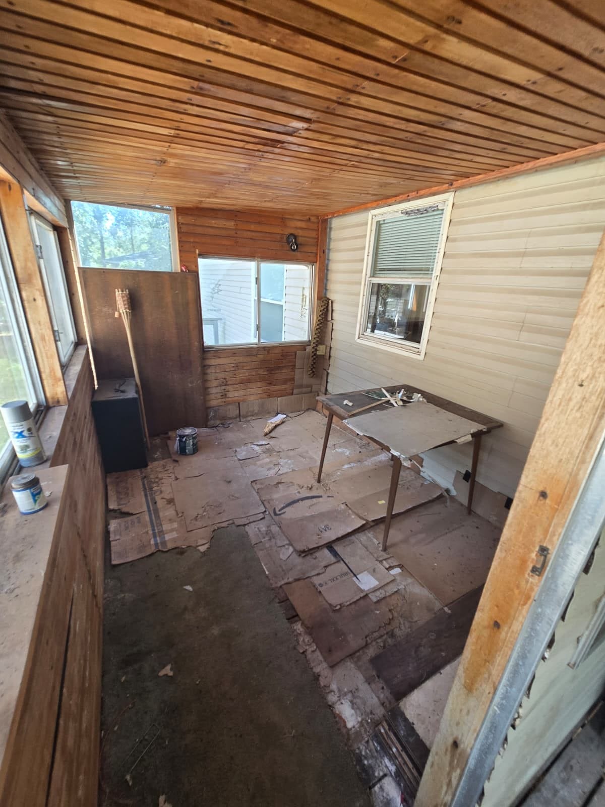 Cozy enclosed porch with wood paneling, ample natural light, and potential for customization.