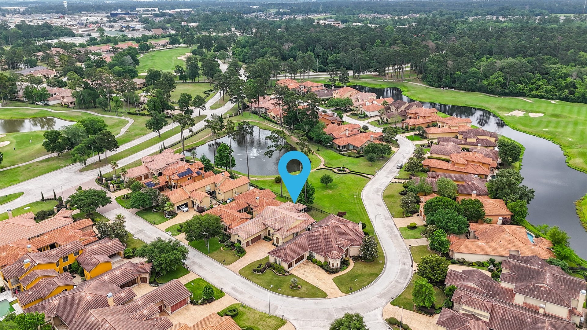 This photo showcases a beautiful suburban neighborhood with a golf course view. The homes have terracotta roofs and are arranged around a curving street, surrounded by lush greenery and a small pond. The area appears peaceful and well-maintained, ideal for someone seeking a scenic and serene residential setting.