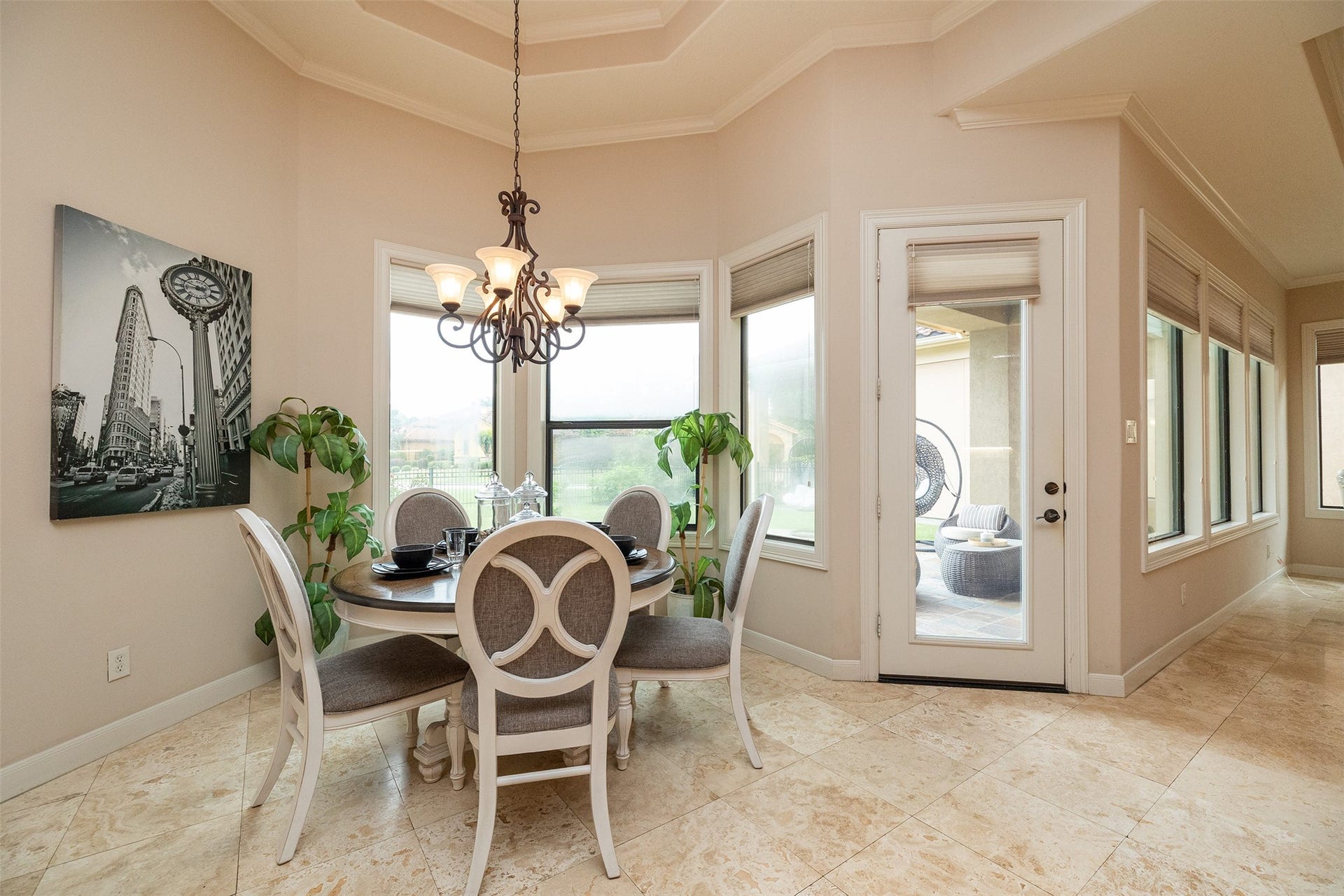 This dining area features elegant tiled flooring, a stylish chandelier, and large windows for ample natural light. It includes a cozy round table with chairs and opens to a patio, ideal for indoor-outdoor living.