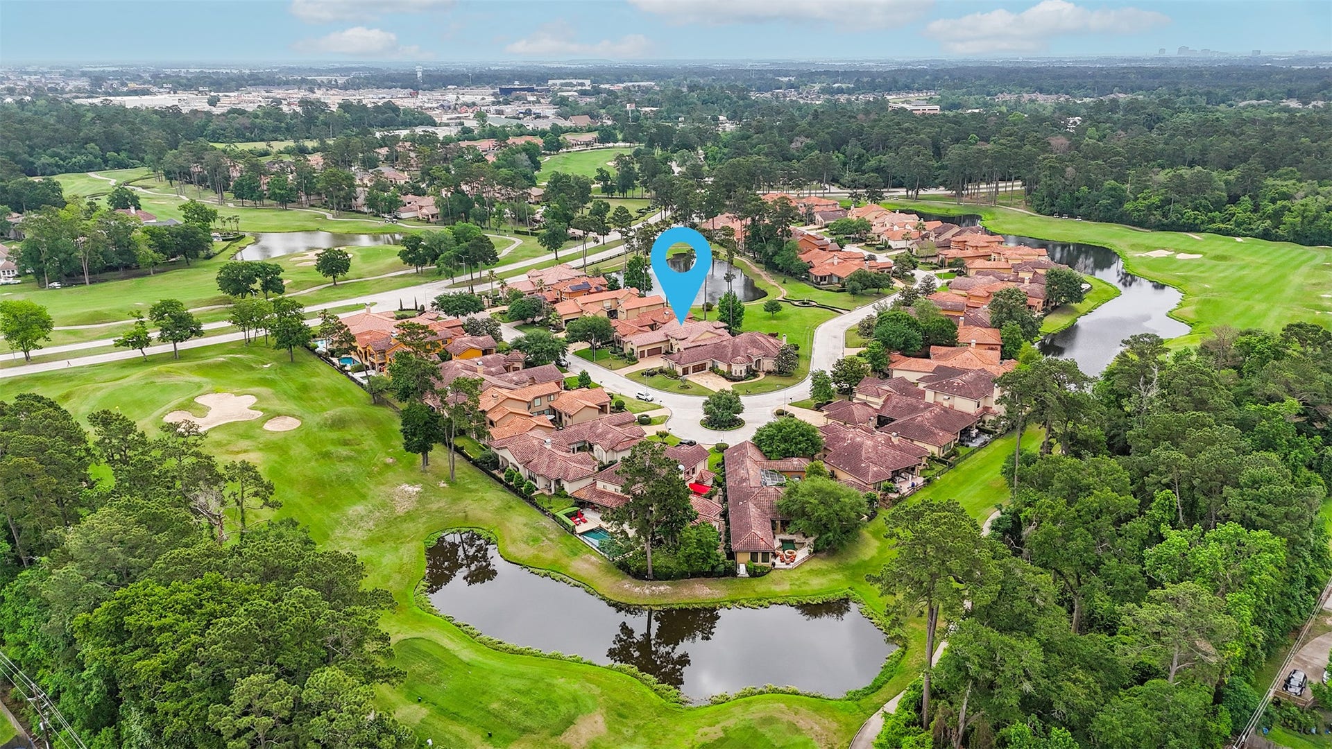 This aerial photo showcases a picturesque residential community with Mediterranean-style homes surrounded by lush greenery and located near a golf course. The area features serene water views and is nestled in a tranquil, well-maintained neighborhood.