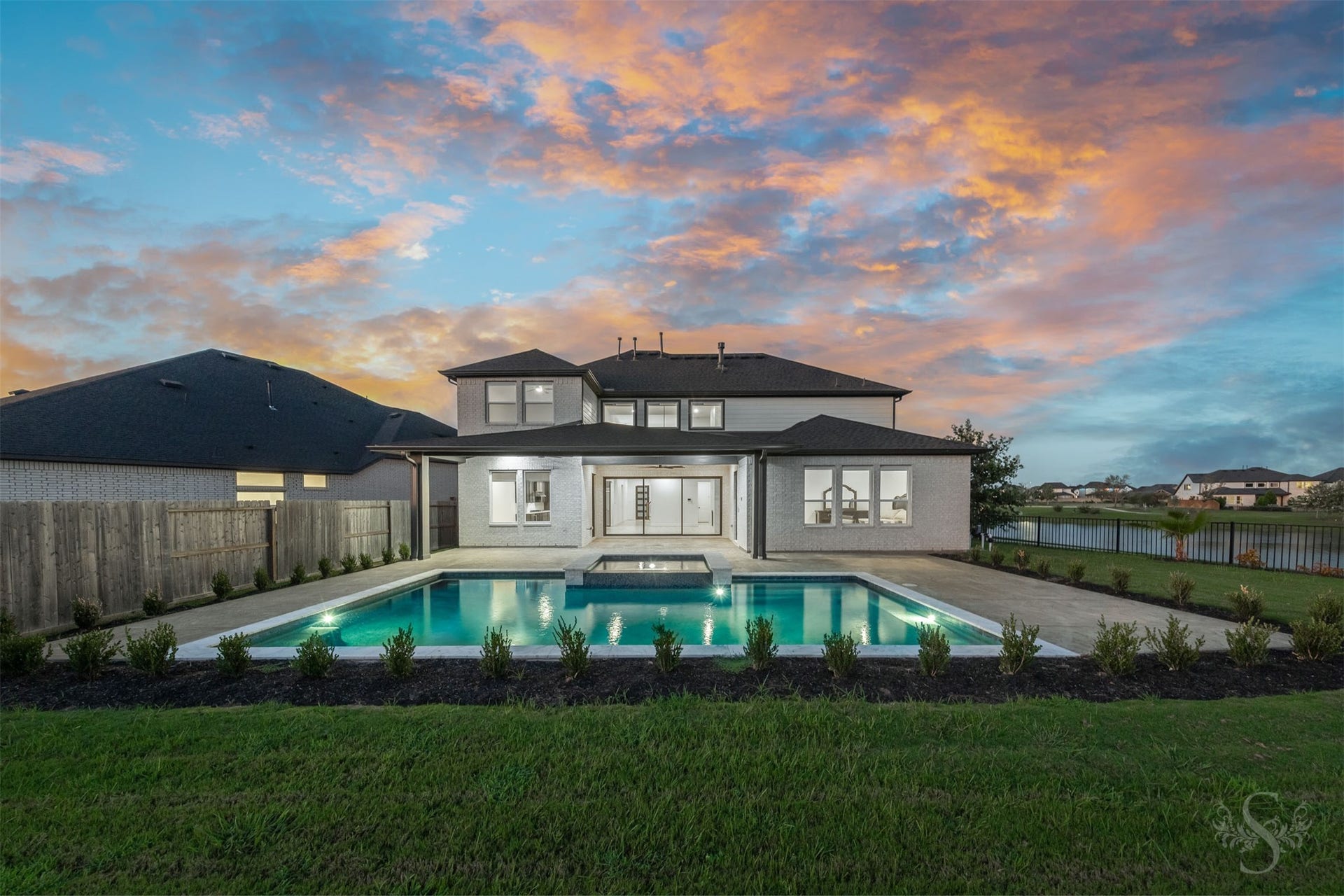 Stunning evening view of the illuminated home and pool.