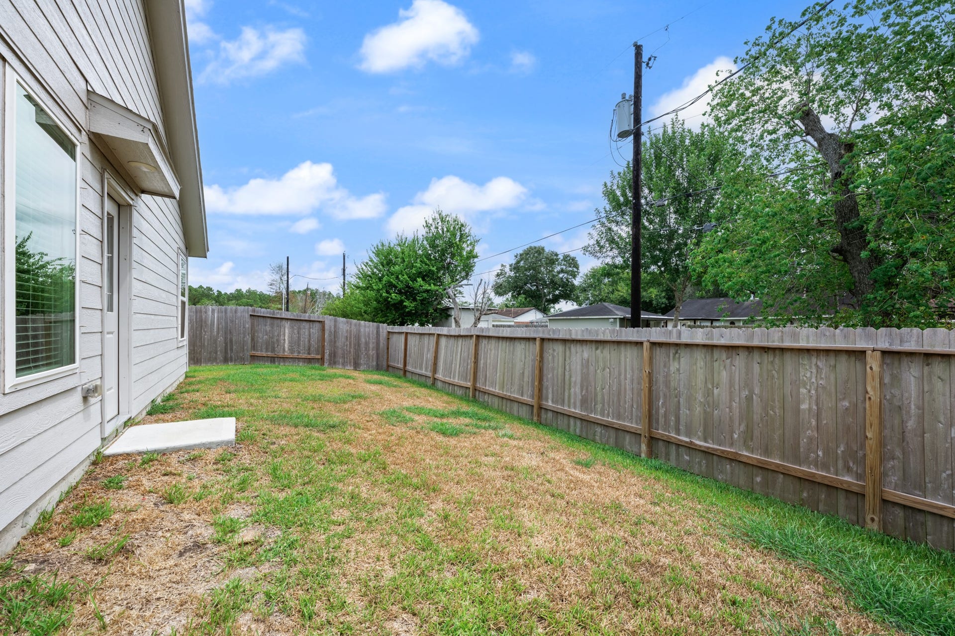 Spacious fenced backyard offers an open lawn area with direct access to the home, providing flexible space for outdoor activities.