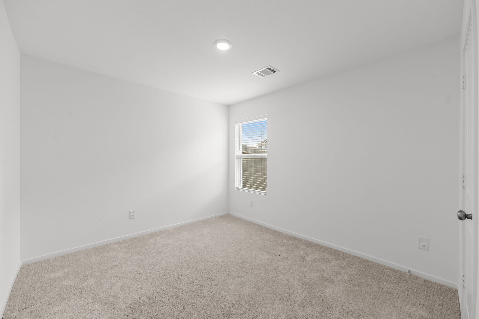Secondary bedroom offers neutral finishes, soft carpeting, recessed lighting, and a window providing natural light.