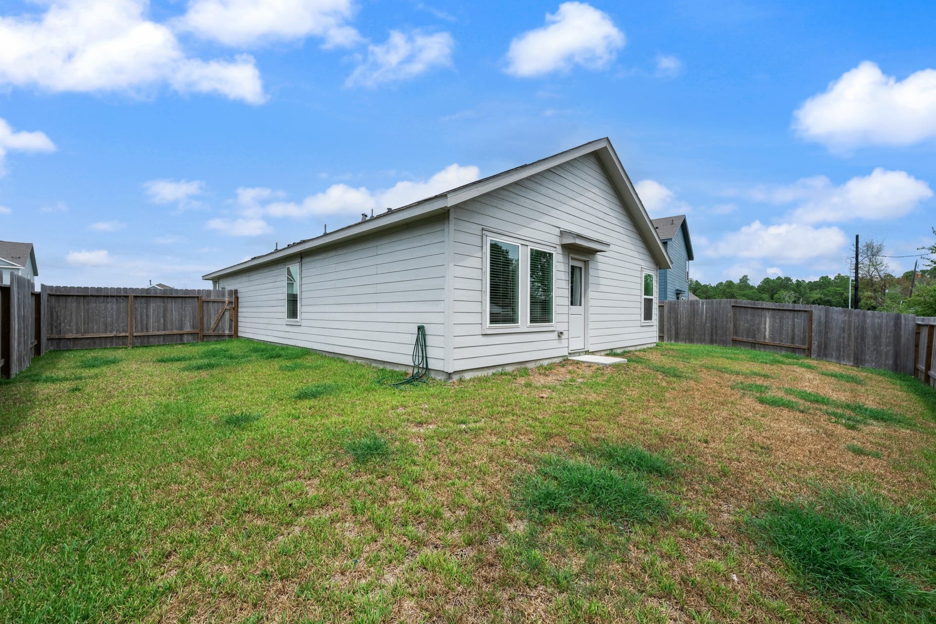 Another perspective showcases the fenced outdoor area and convenient rear entry to the home.