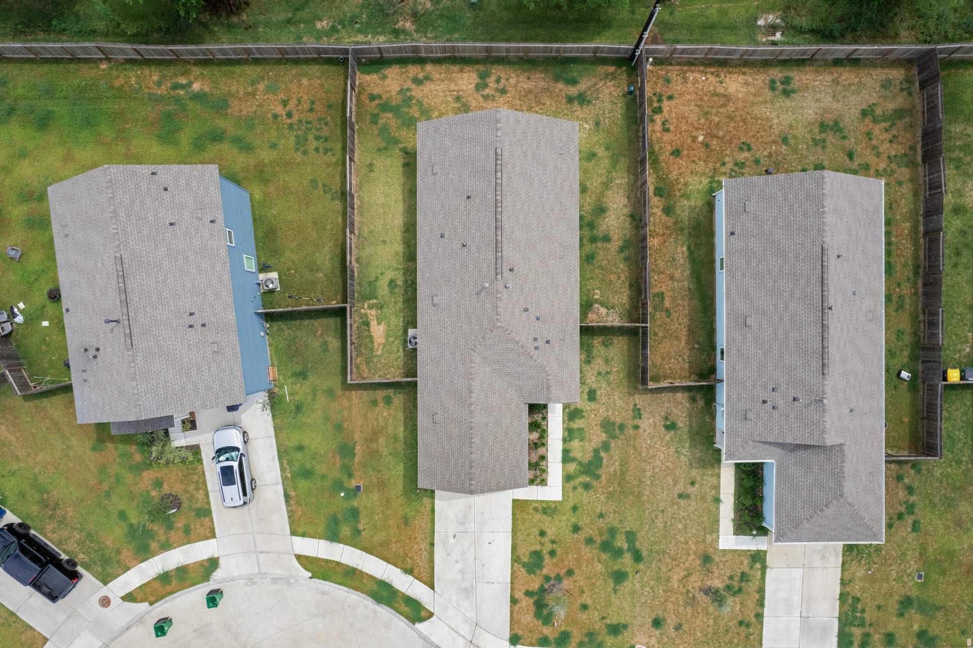 Top-down aerial perspective provides a clear look at the homes placement, driveway, yard, and fenced rear portion of the property.