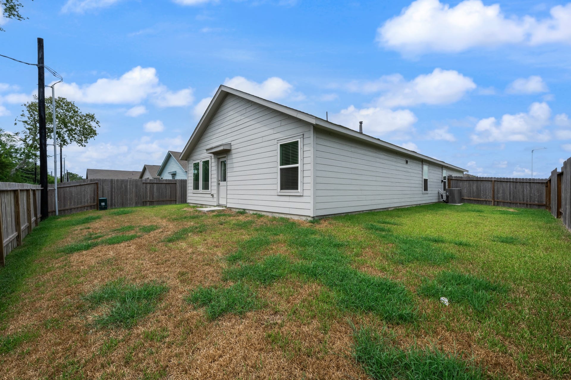 Wide rear view highlights the single-story exterior, backyard space, and privacy fencing surrounding the property.