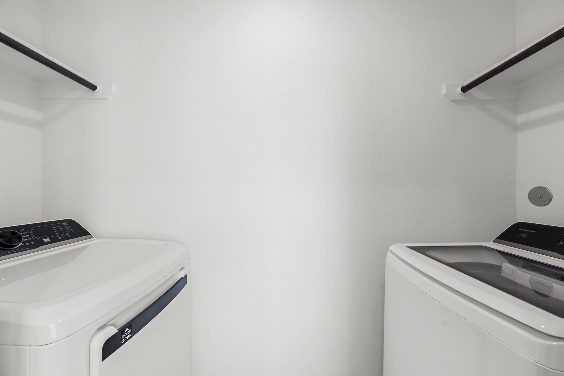 Dedicated laundry space accommodates a washer and dryer with hanging rods above for additional utility.