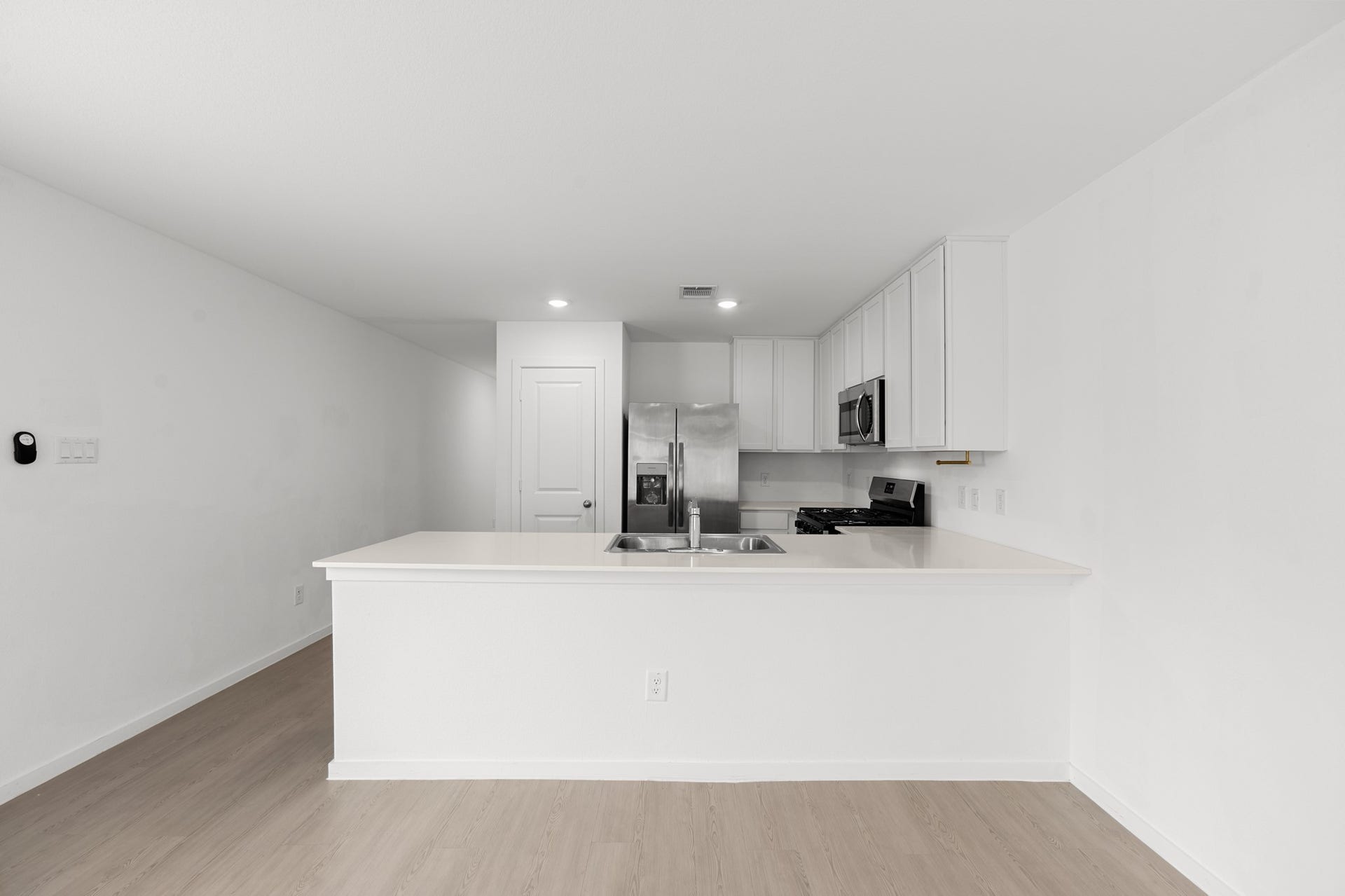 Expansive peninsula provides ample prep and serving space while keeping the kitchen visually connected to the surrounding living areas. Crisp white cabinetry pairs with stainless steel appliances for a streamlined finish.