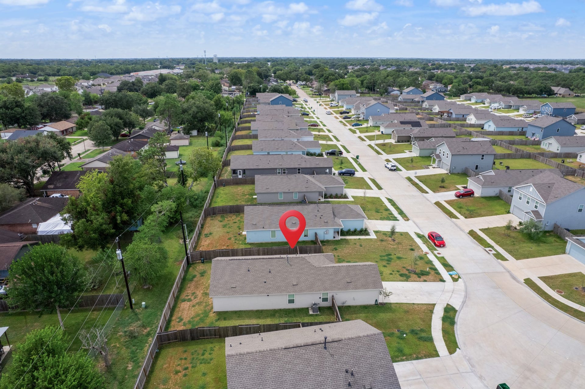 Closer aerial perspective highlights the property and its fenced backyard while showing the surrounding streets and neighboring homes.