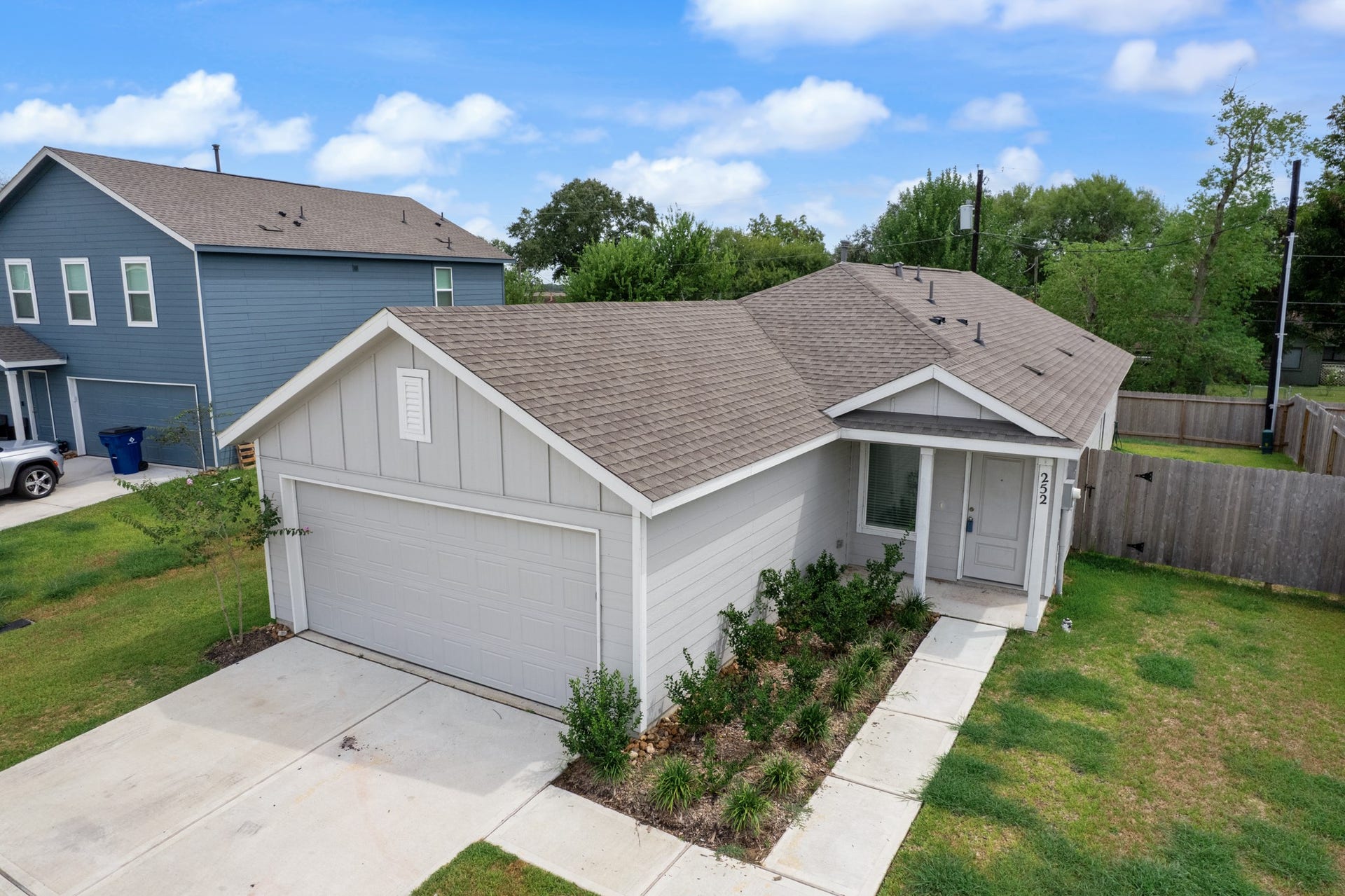 Elevated exterior view showcases the homes single-story design, two-car garage, covered front entry, and landscaped walkway.