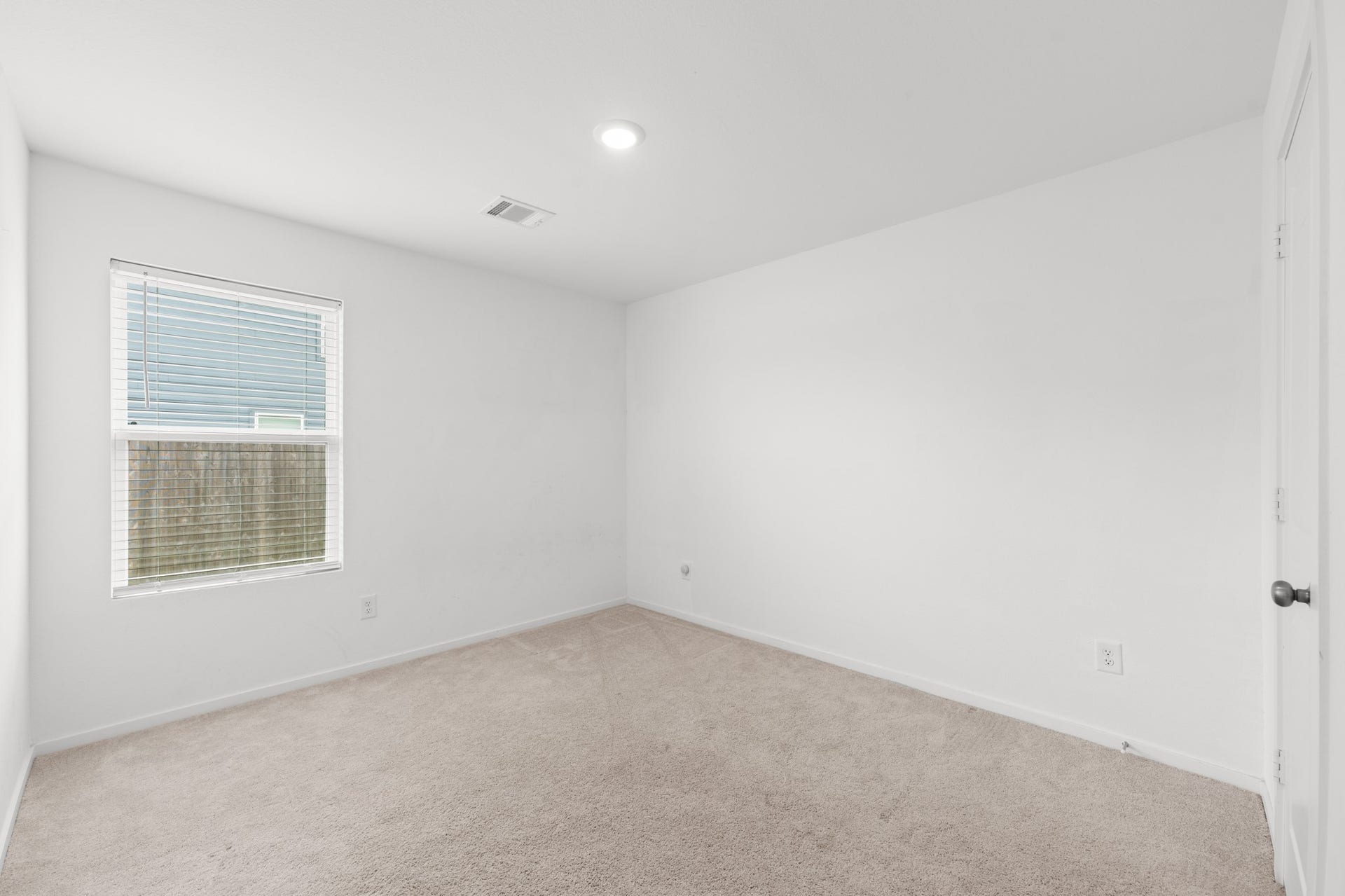 Alternate view highlights the bedrooms versatile layout, neutral carpeting, and ample wall space for furniture placement.