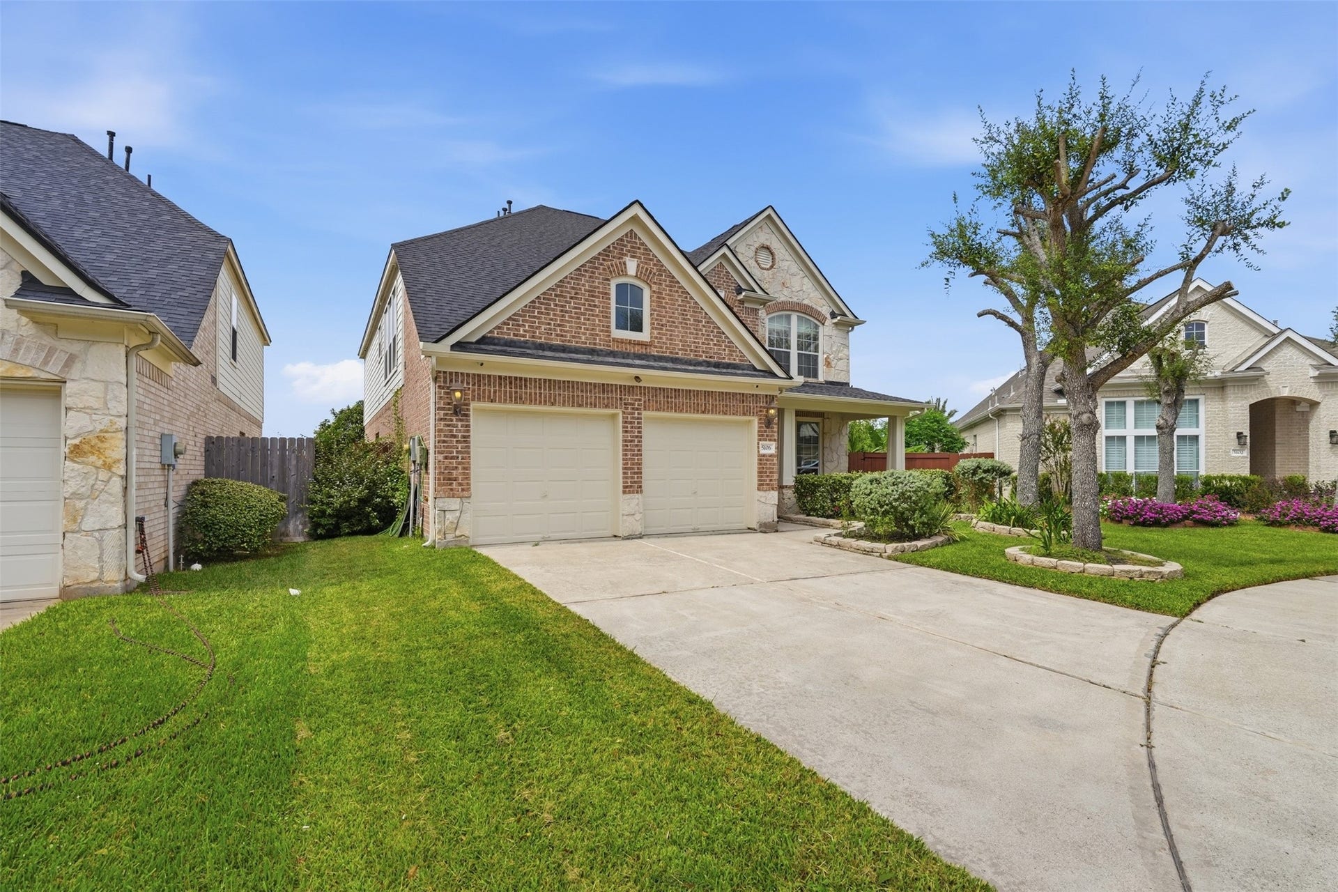 5106 Autumn Rose Lane, Sugar Land, TX 77479 A wide driveway and two-car garage, with a side gate leading to the fully fenced backyard.