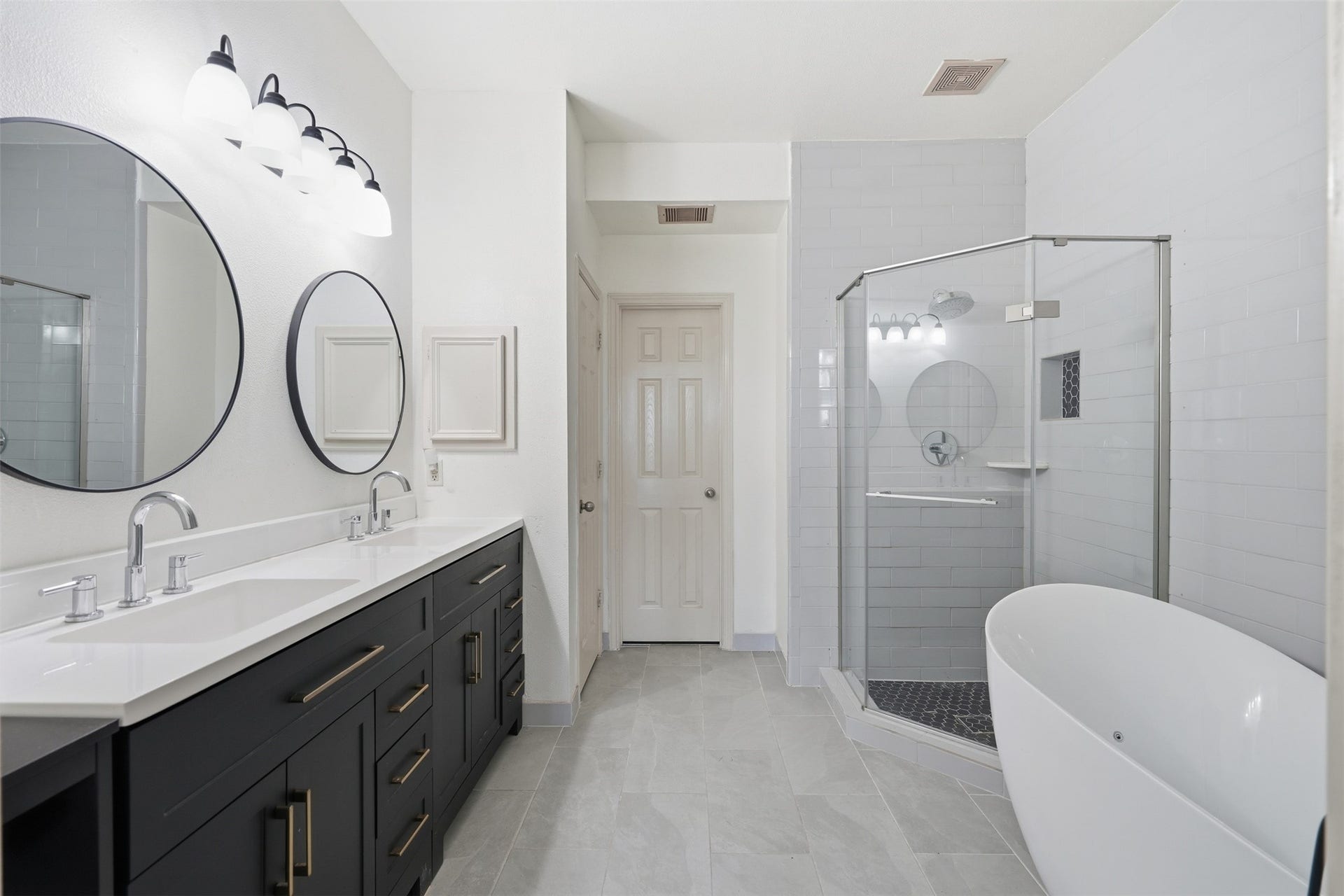 5106 Autumn Rose Lane, Sugar Land, TX 77479 The remodeled primary bath feels like a retreat: a double vanity, a freestanding soaking tub and a walk-in glass shower.