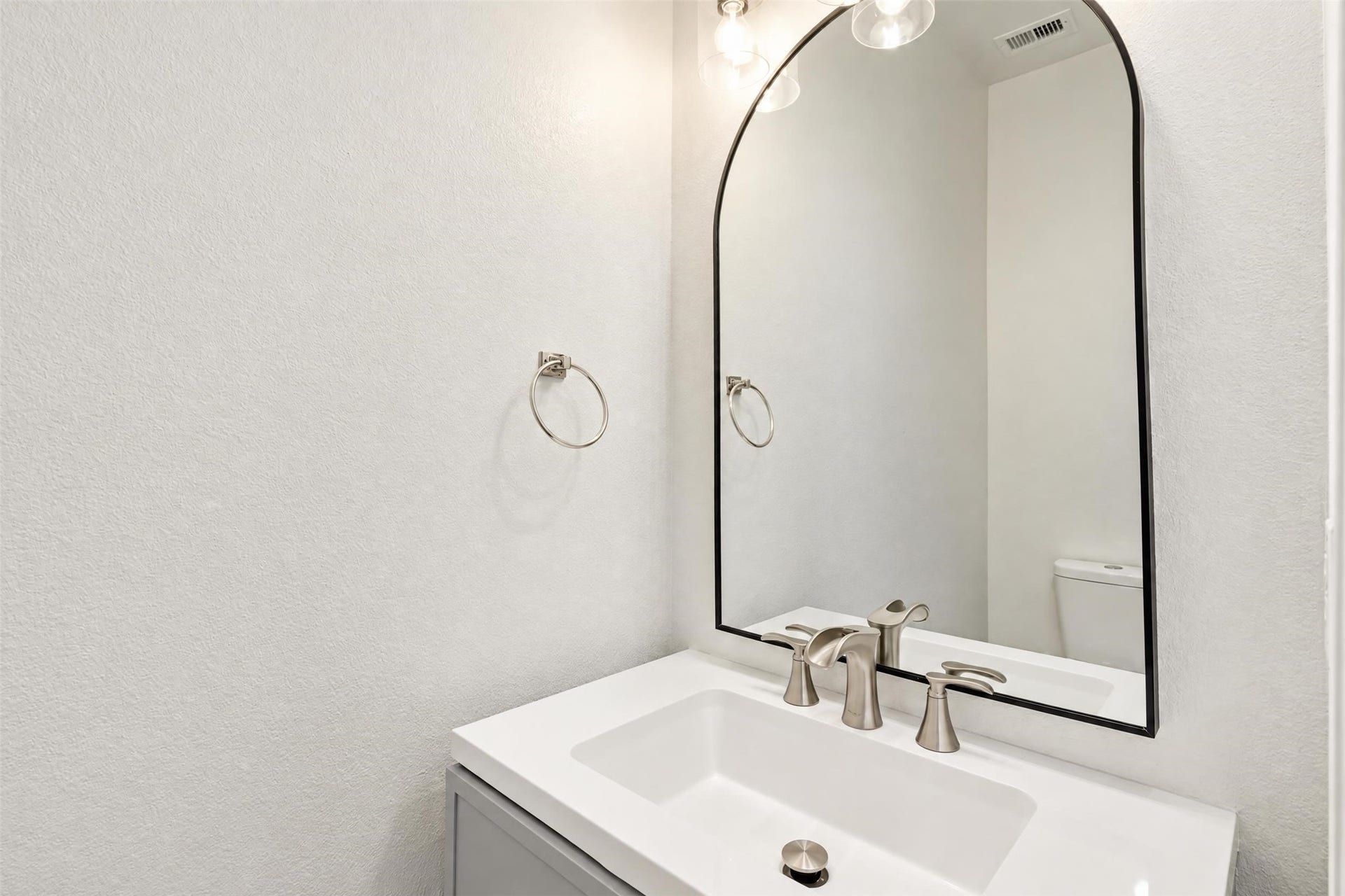 5106 Autumn Rose Lane, Sugar Land, TX 77479 Updated powder room on the main floor for guests, with a modern vanity and an arched mirror.