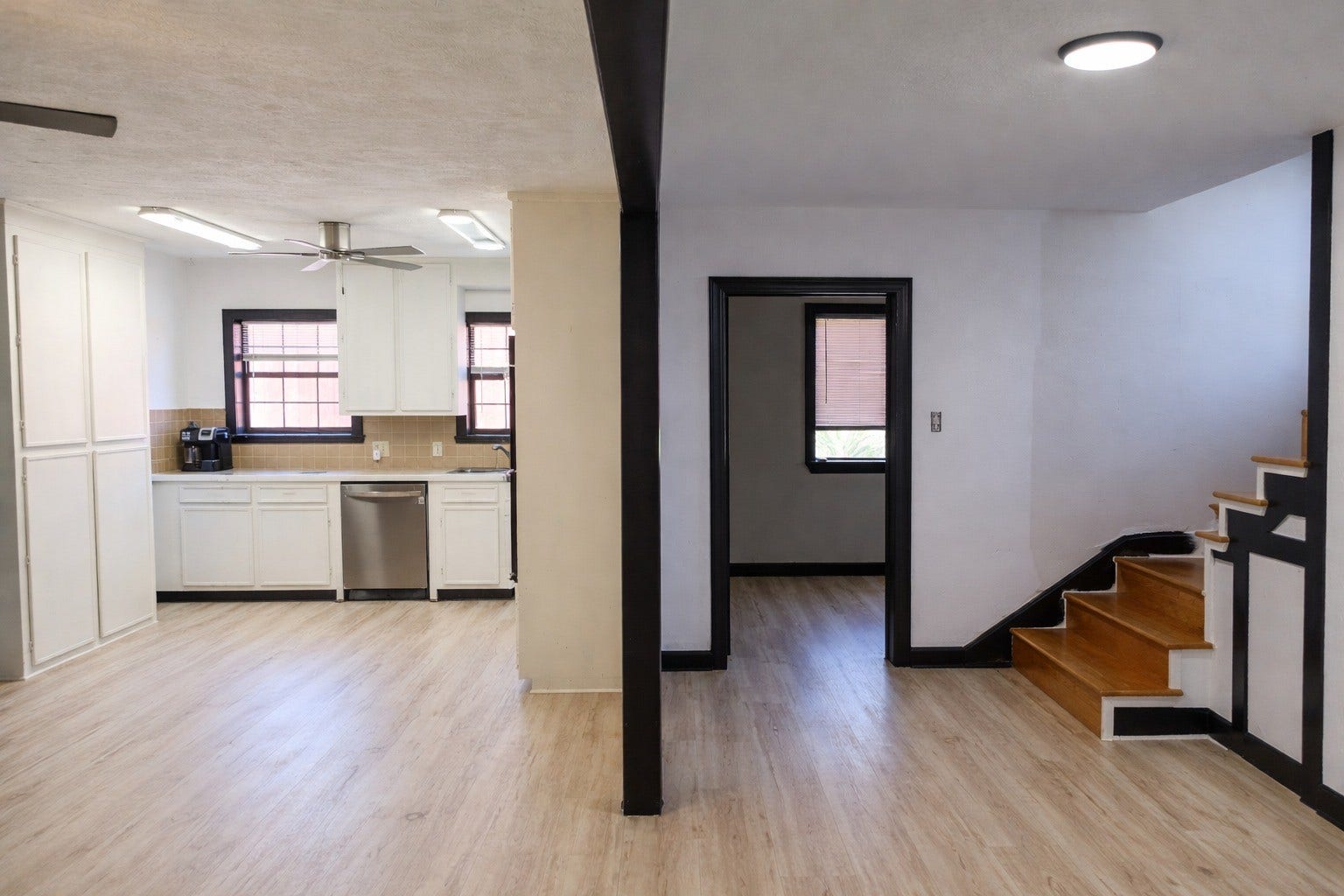 Wide open-concept layout showing seamless flow between the main living area, kitchen space, and adjacent staircase.