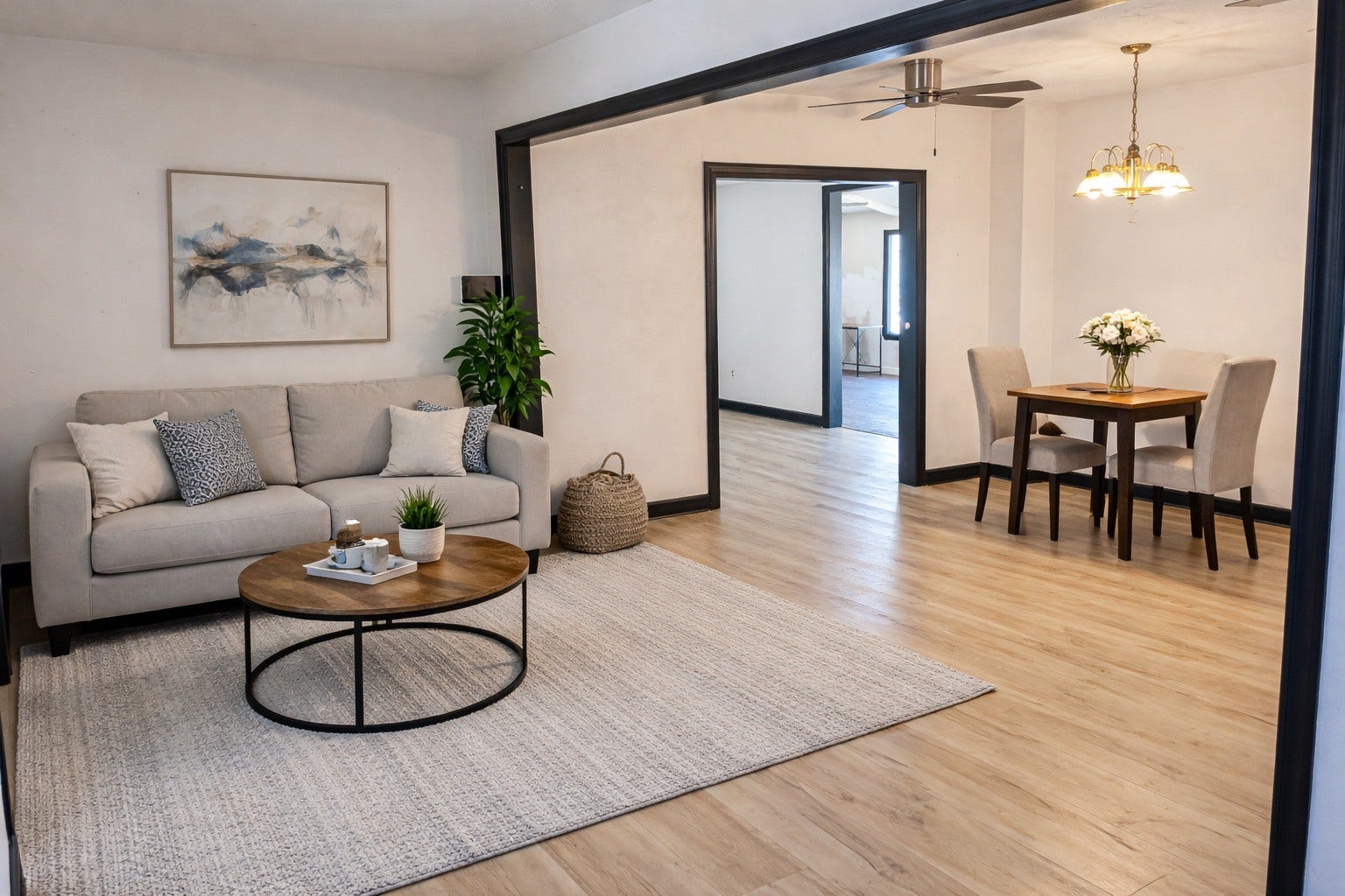 STAGED. Warmly staged living room showcasing bright open layout, comfortable seating space, light plank flooring, and a dedicated dining nook.