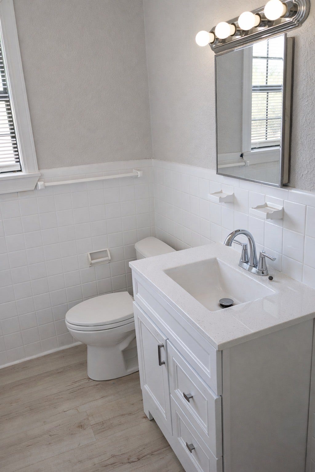 Alternate view of the renovated bathroom showcasing the updated single-sink vanity, brushed nickel faucet, mirror cabinet, and light-filled window.