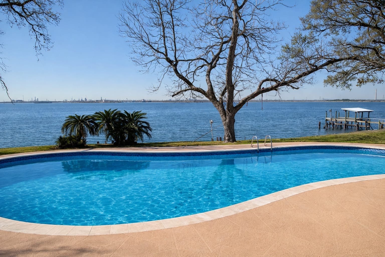 Gorgeous sparkling outdoor pool and patio area boasting breathtaking, unobstructed open-water views and framed by mature trees.