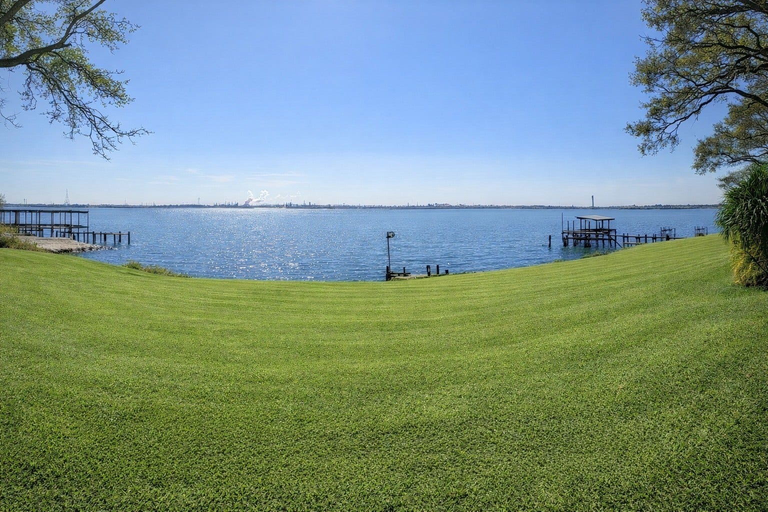Sprawling, lush green backyard lawn extending directly toward the shoreline with panoramic bay views.