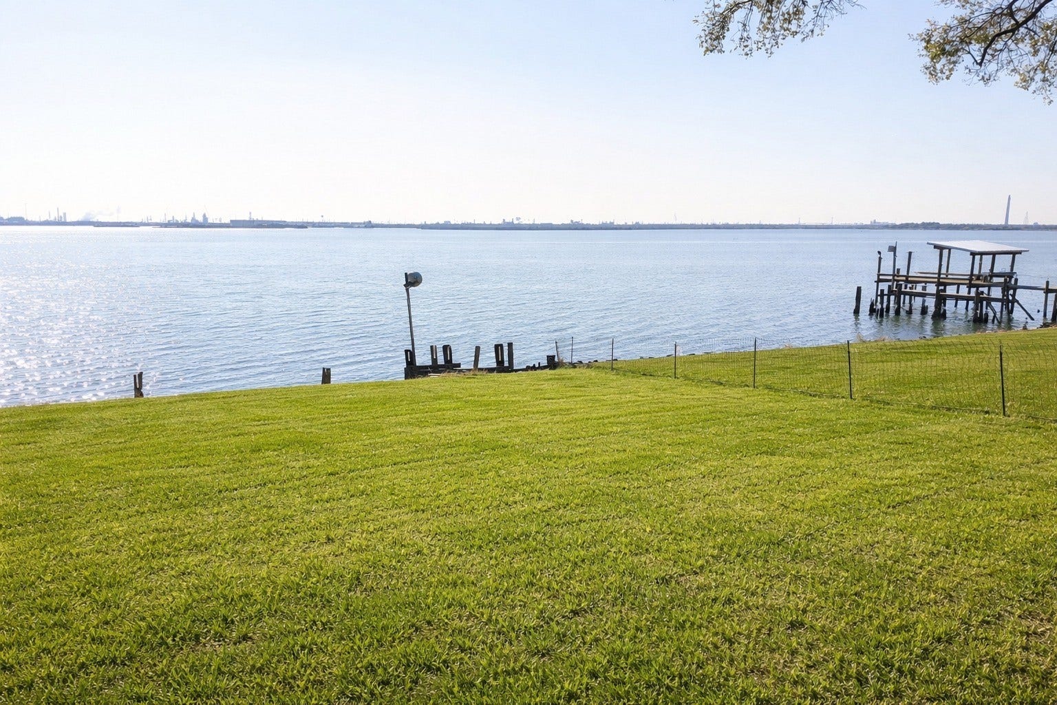 Crisp daytime shoreline shot showcasing the manicured lawn edge, bulkhead, and vast open water views