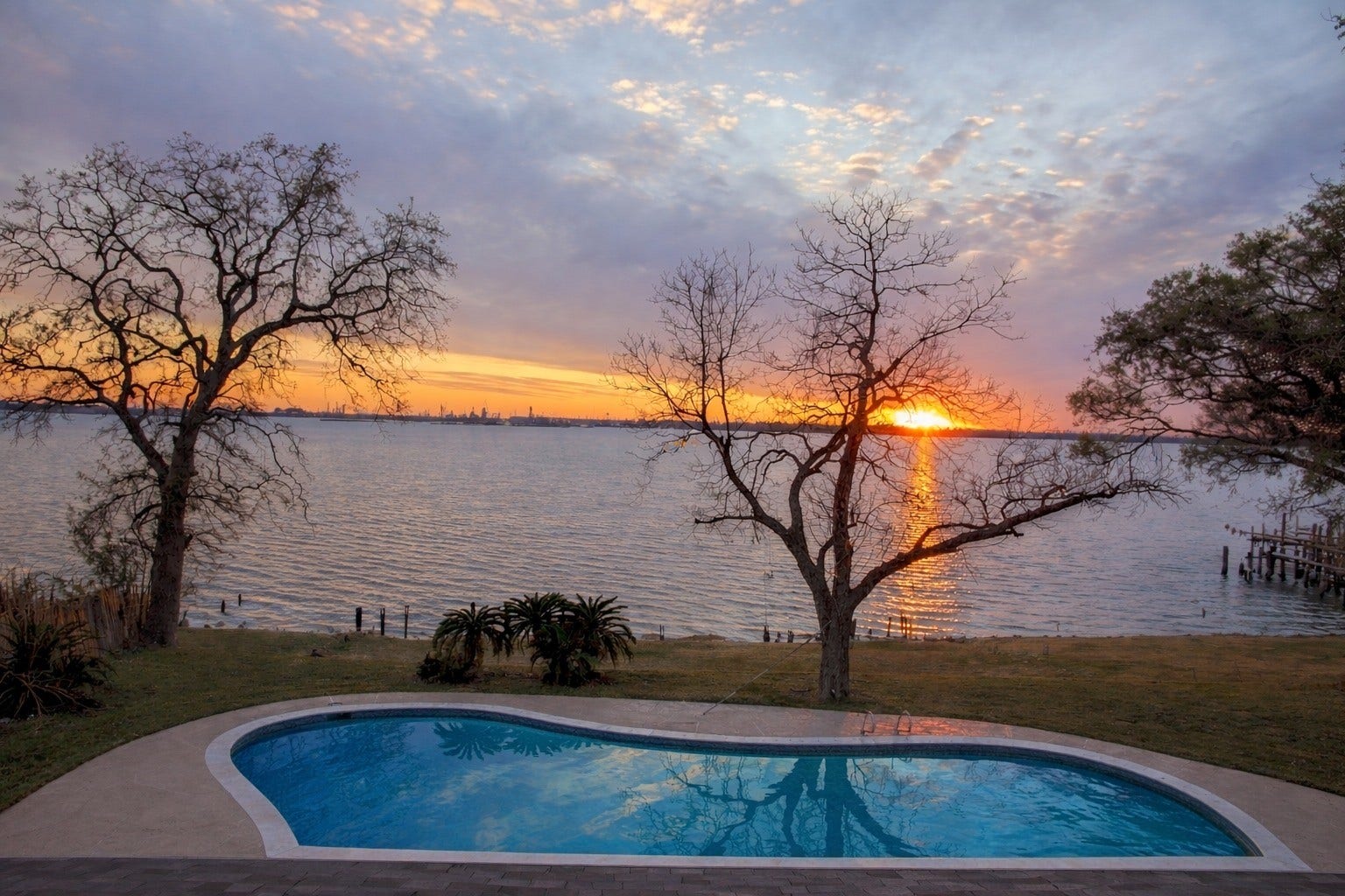 Breathtaking evening view over the sparkling backyard pool, showcasing spectacular sunsets across open waters.