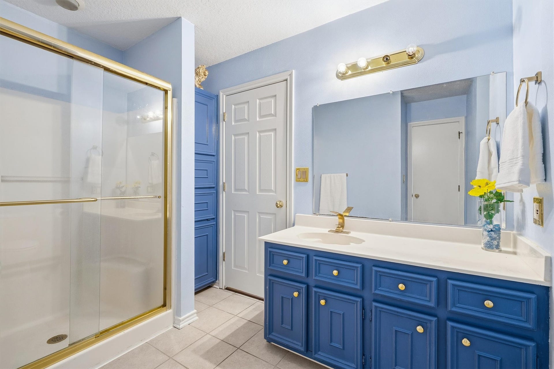 149 Thunderbird Drive, Conroe, TX 77304 The secondary bath brings a pop of color with navy cabinetry and a built-in linen tower that keeps towels and essentials within easy reach.