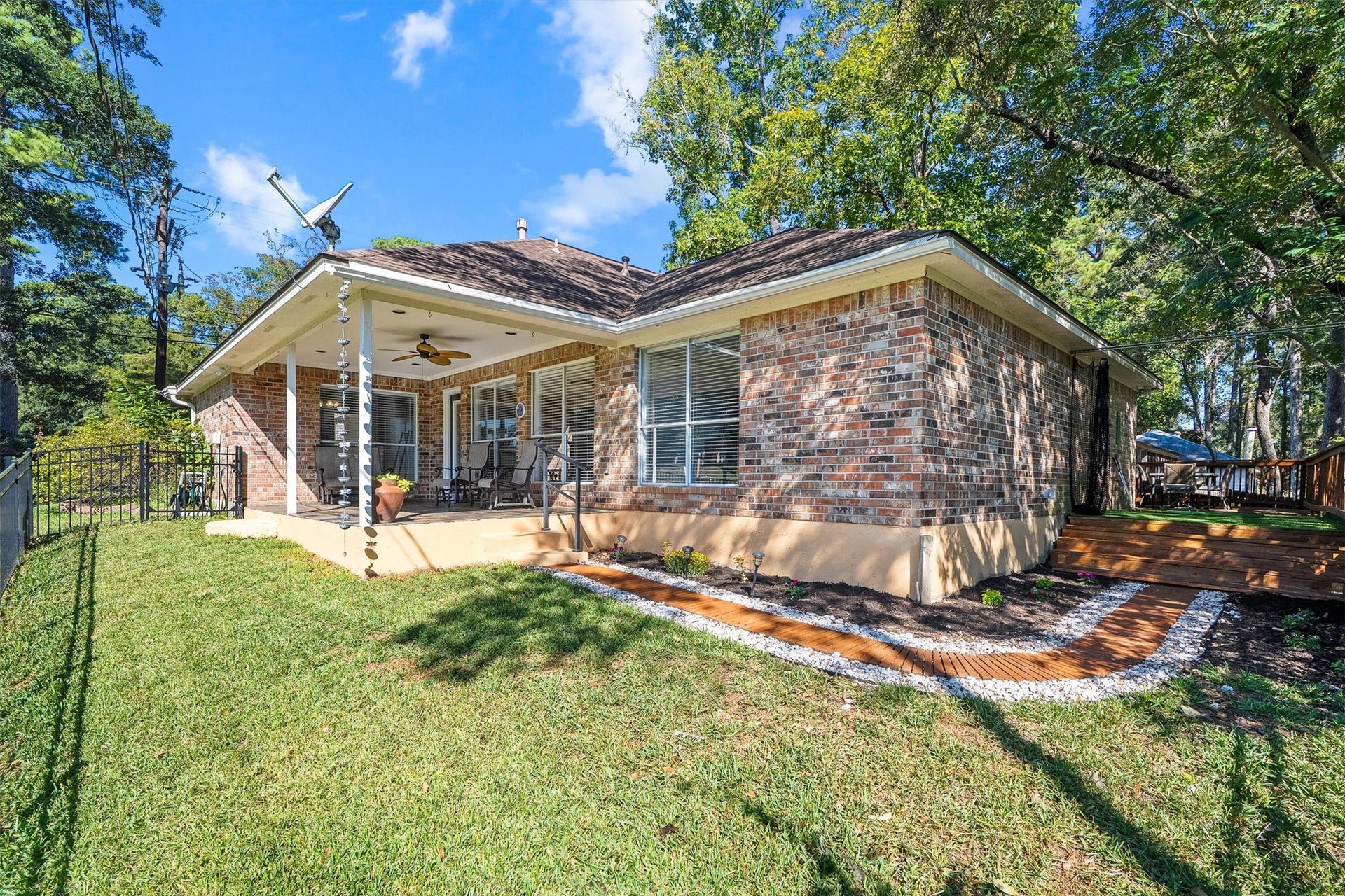149 Thunderbird Drive, Conroe, TX 77304 Freshly landscaped beds wrap around the back of the home, edged in river rock with a wood plank path running through the garden.