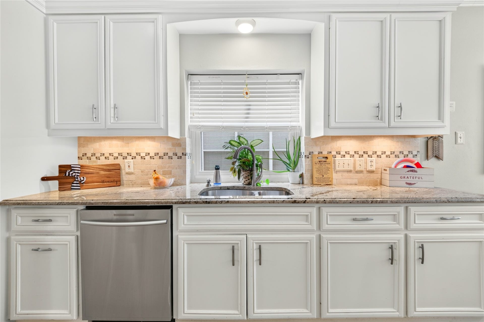 Granite countertops, white cabinetry and a window overlooking outside.