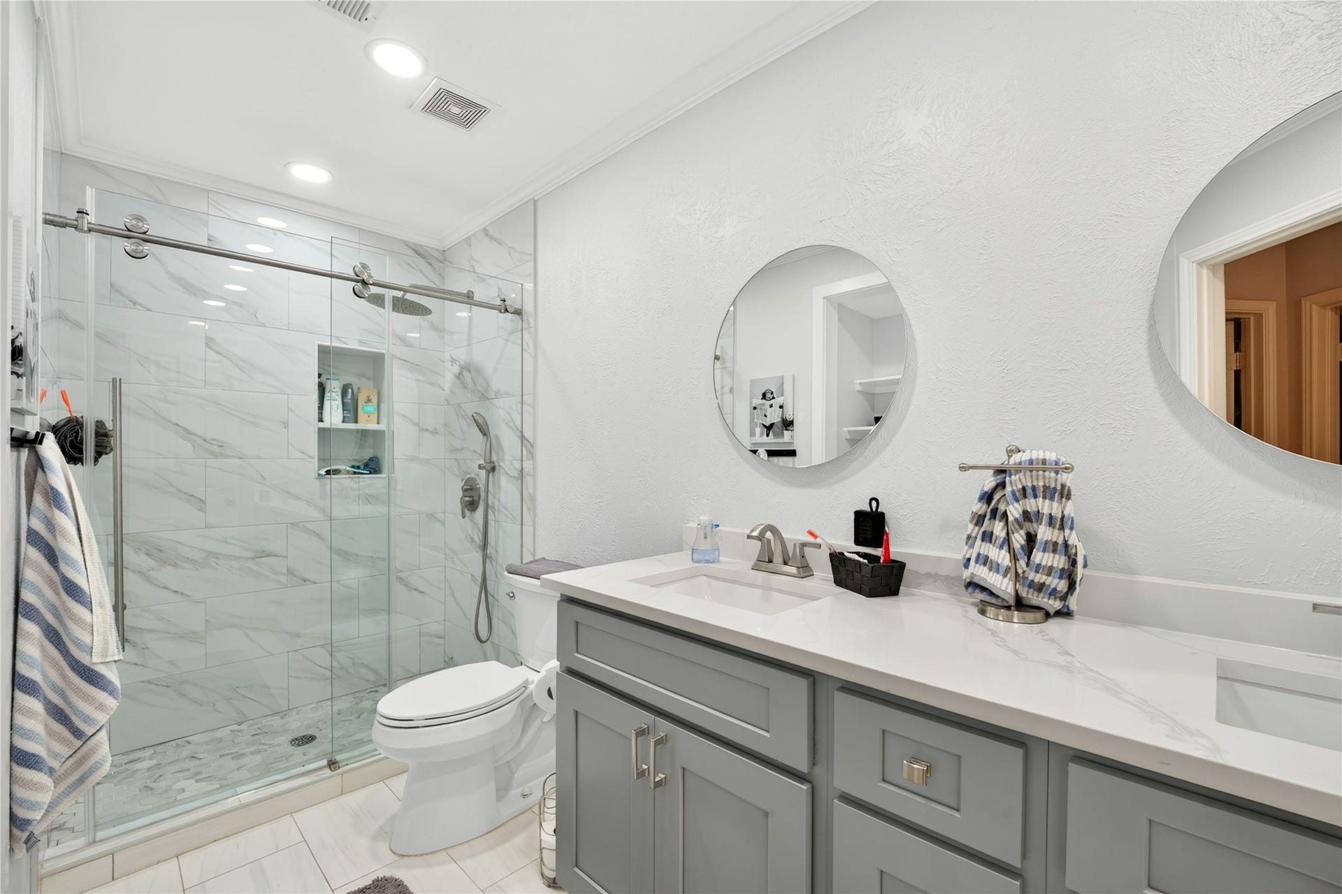 Updated secondary bathroom with dual sinks and oversized glass-enclosed shower.