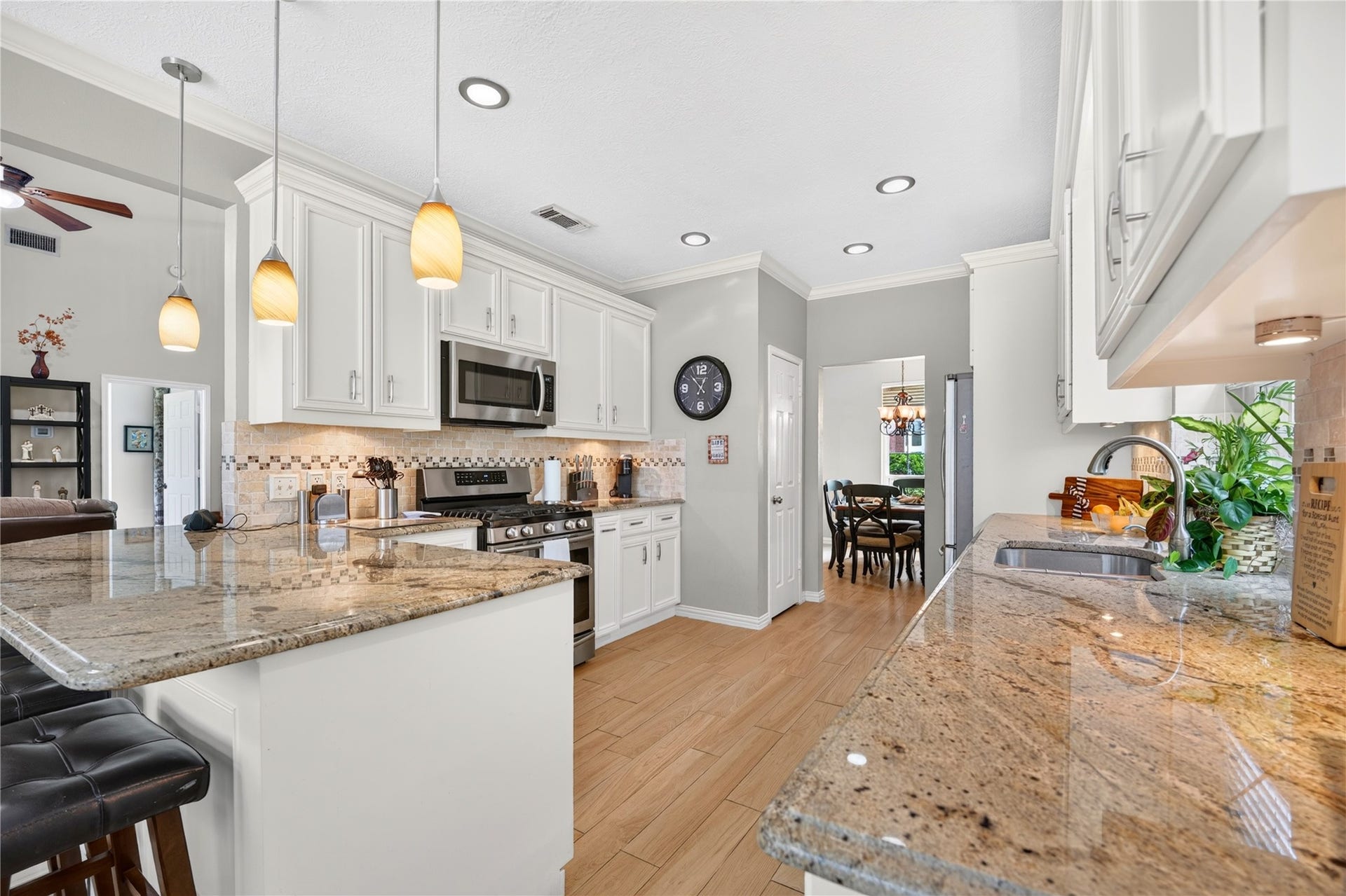 Spacious kitchen featuring granite countertops, abundant white cabinetry, stainless steel appliances and an extended breakfast bar with seating.