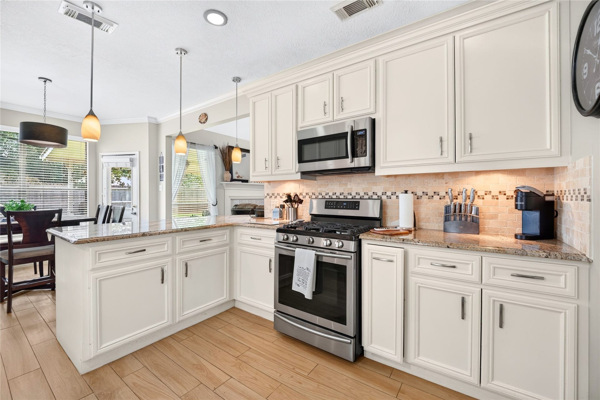 Bright kitchen featuring granite countertops, abundant cabinetry, stainless steel appliances and pendant lighting.