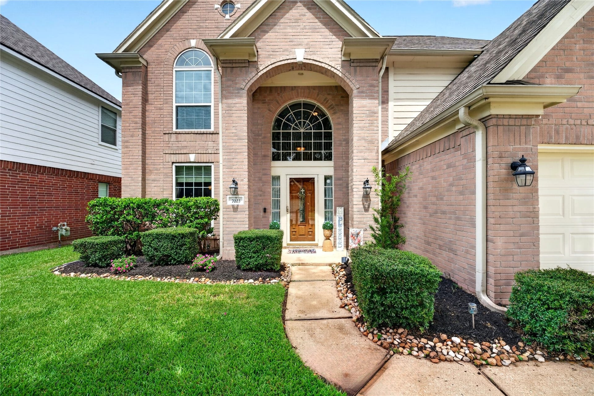 Welcoming front entry with arched architectural details and manicured landscaping.
