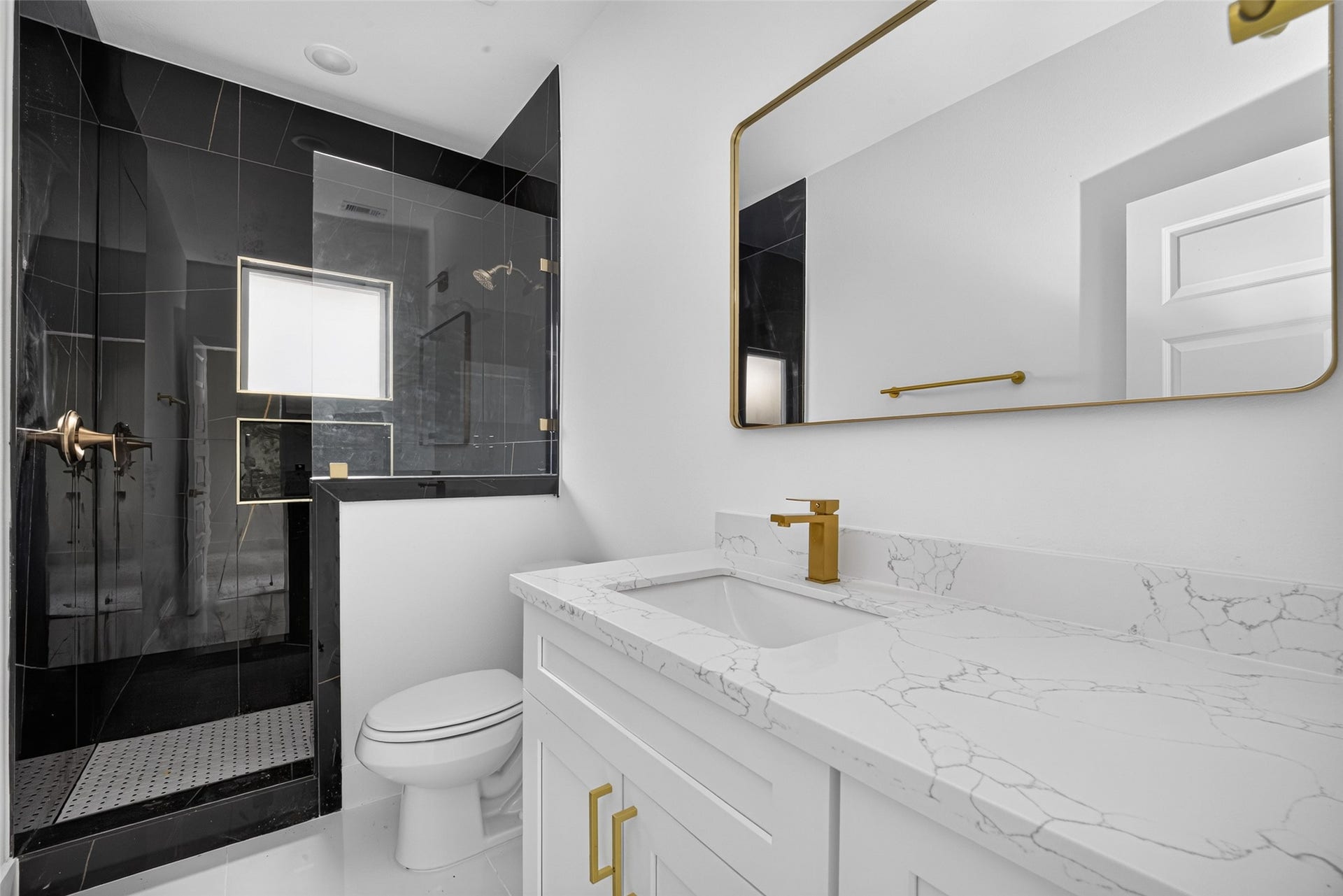 9309 Caddo Road, #B, Houston, TX 77078 Modern luxury meets daily functionality with a dark marble-look walk-in shower, bright quartz vanity, and elevated gold hardware.