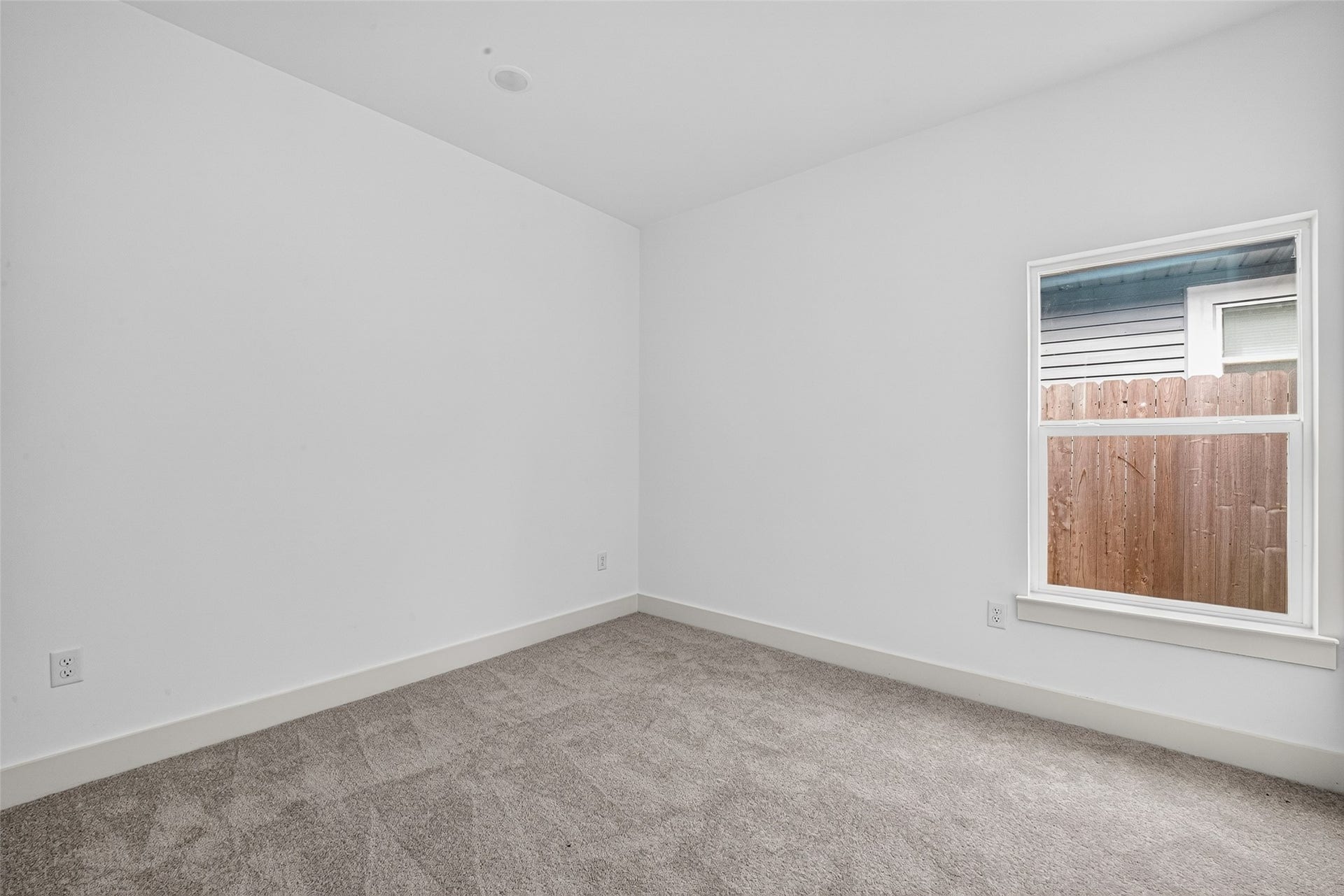 9309 Caddo Road, #B, Houston, TX 77078 Secondary bedroom #1: A quiet, cozy retreat designed for restful nights. Soft neutral walls and plush carpeting create a peaceful atmosphere, while a bright window frames serene views of your private fenced backyard.