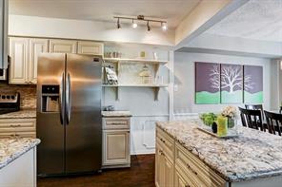 Stainless appliances, including a large capacity double-door fridge. Additional shelving is decorative and functional
